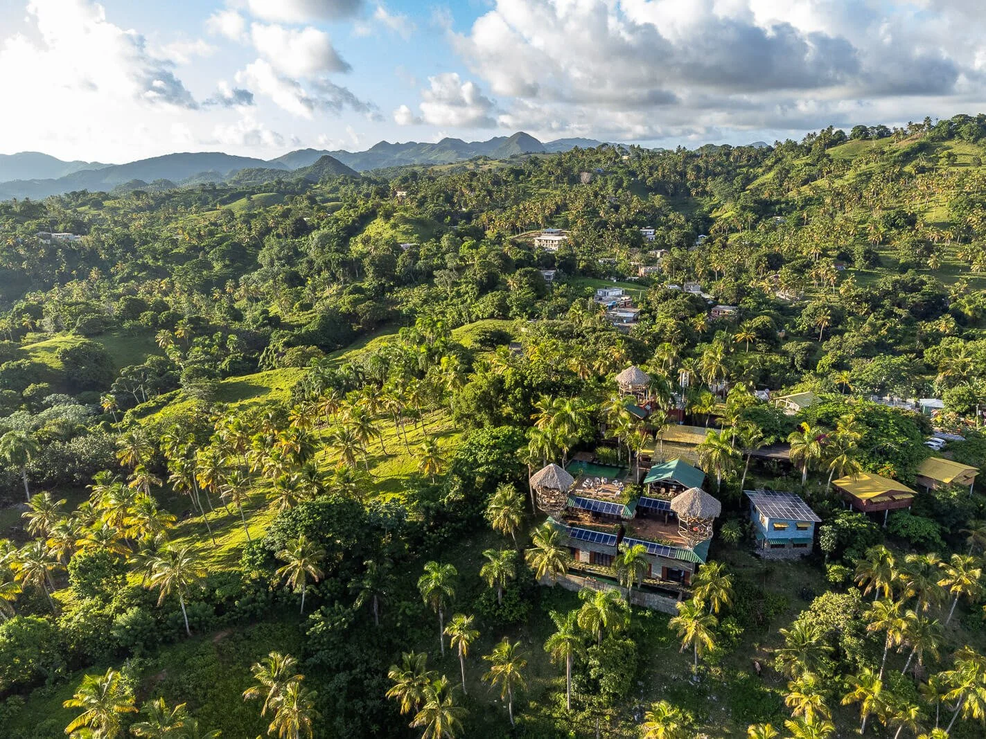  Hacienda Cocuyo bei Monte Rojo aus der Drohnenperspektive, eingebettet in grüne Hügellandschaft oberhalb der Bucht von Samaná 