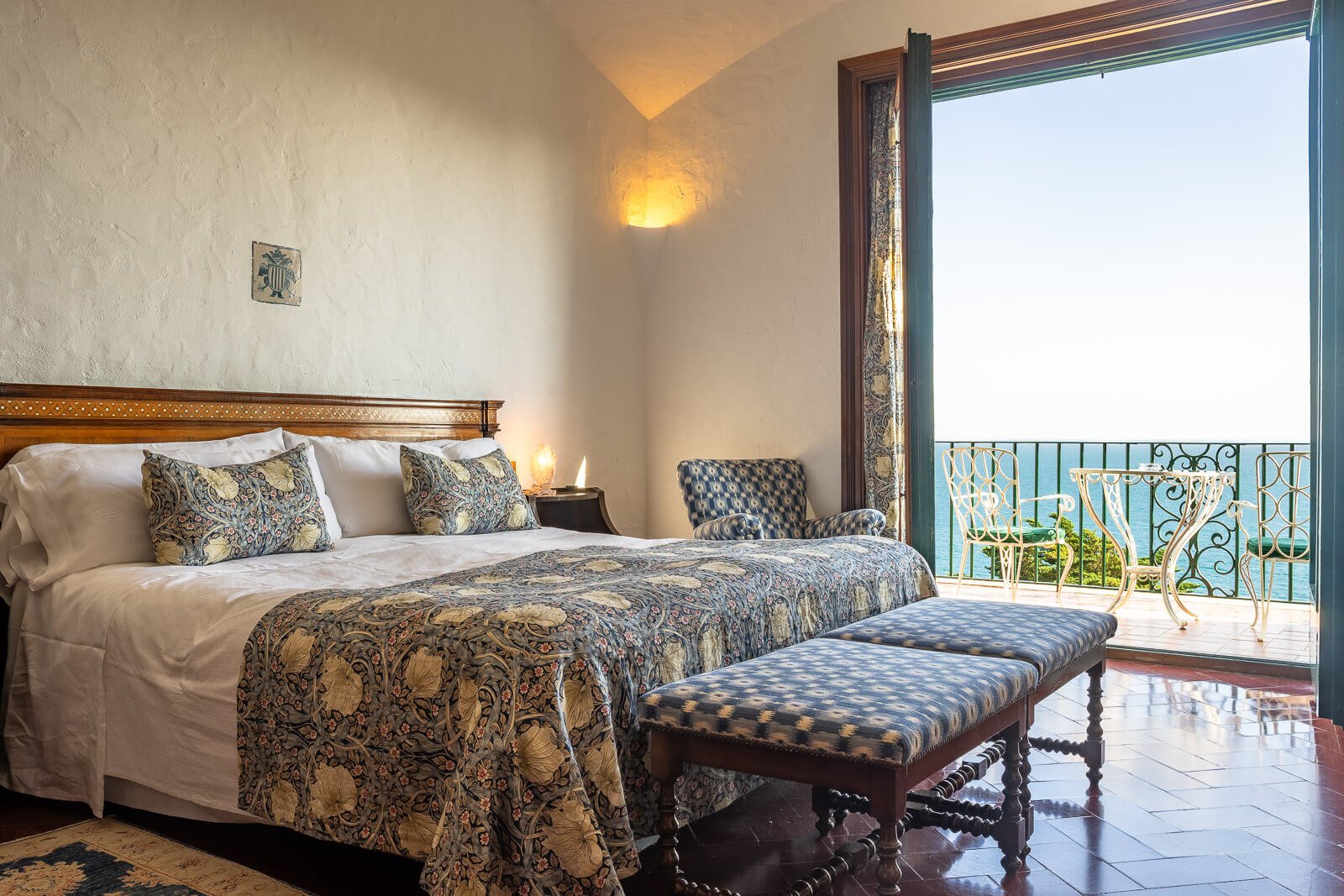 Charmantes Boutique-Hotelzimmer mit Meerblick, Balkon und gemustertem Interieur – hochwertige Zimmerfotografie.