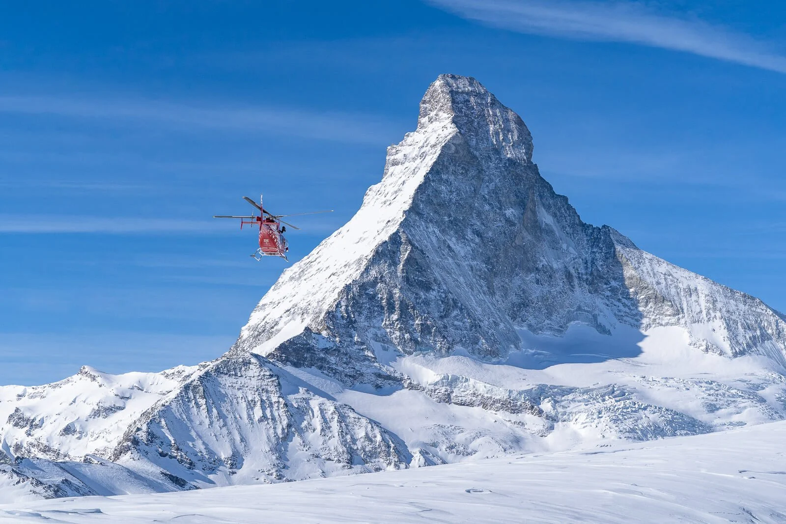 Helikopter der Air Zermatt fliegt auf das winterliche Matterhorn zu