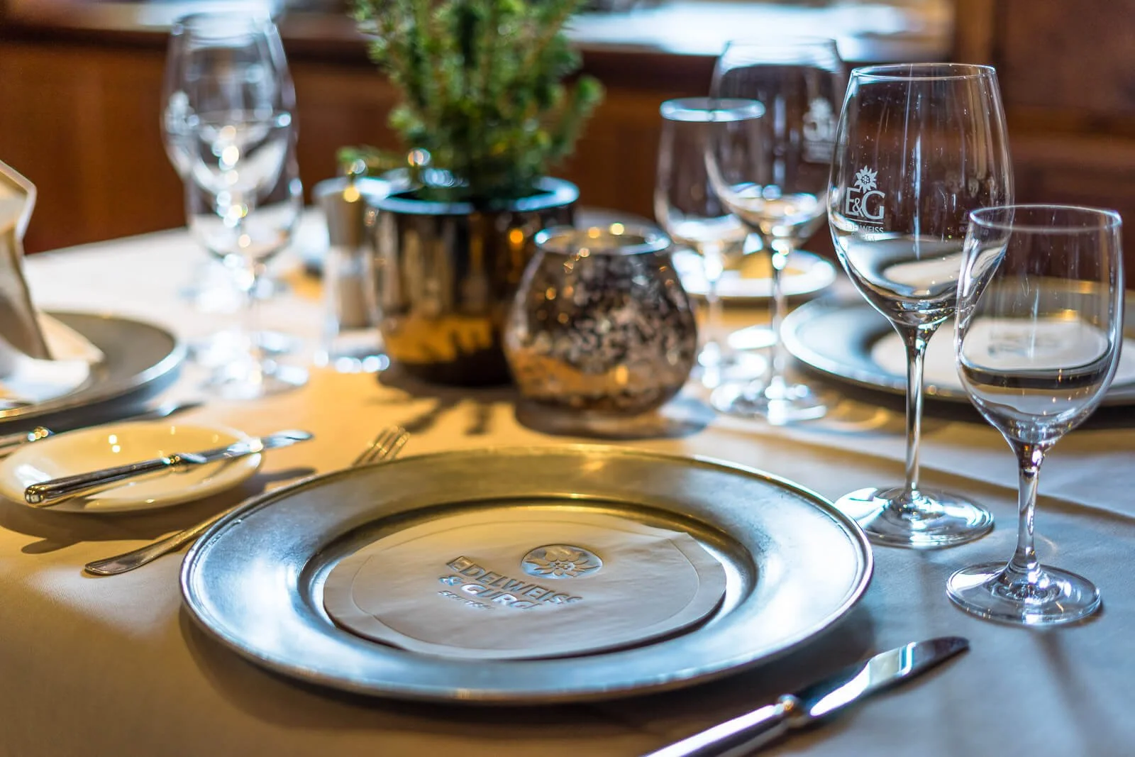 Elegant gedeckter Restauranttisch mit Gläsern und edlem Platzteller in einem alpinen Hotel in Tirol.