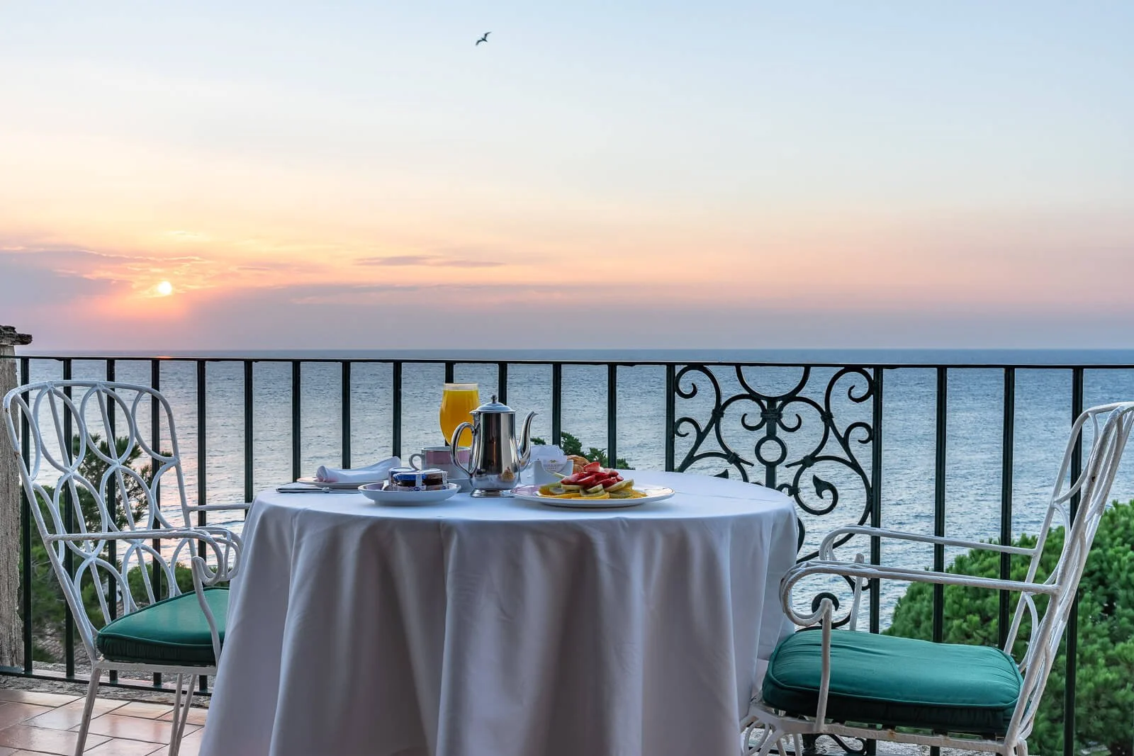 Frühstückstisch bei Sonnenaufgang auf einem Hotelbalkon mit Meerblick an der Costa Brava in Spanien.