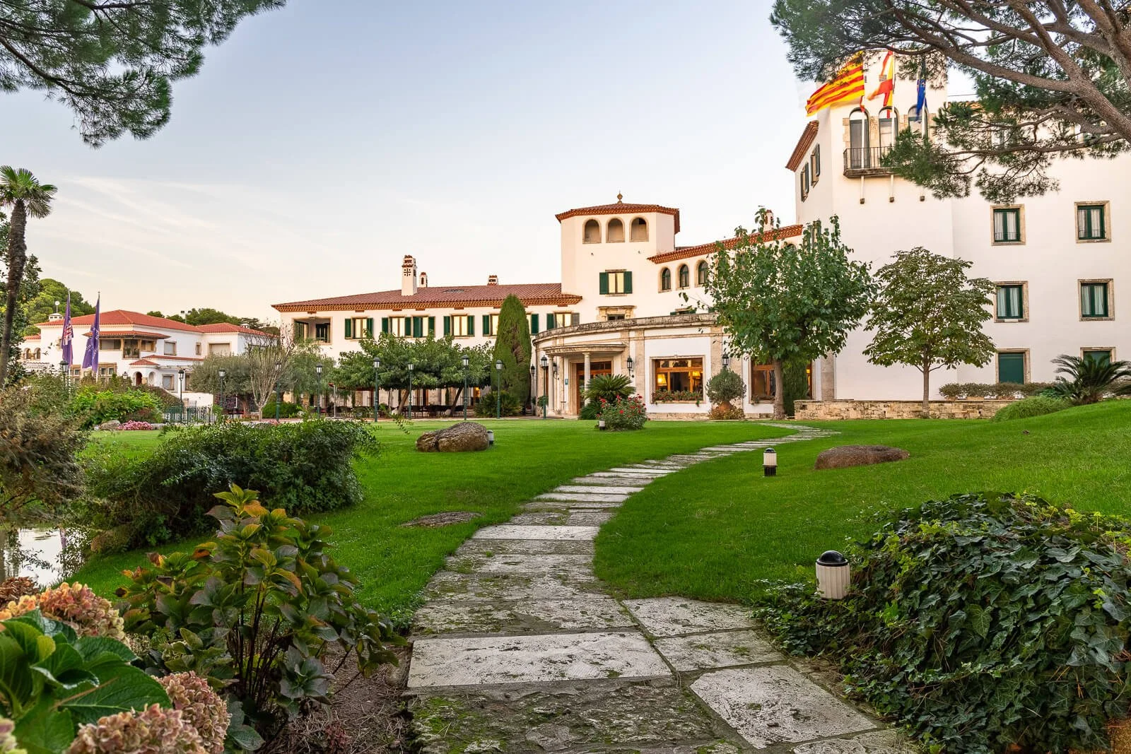 Elegantes Hotelgebäude in Spanien mit gepflegtem Garten und warmem Abendlicht.