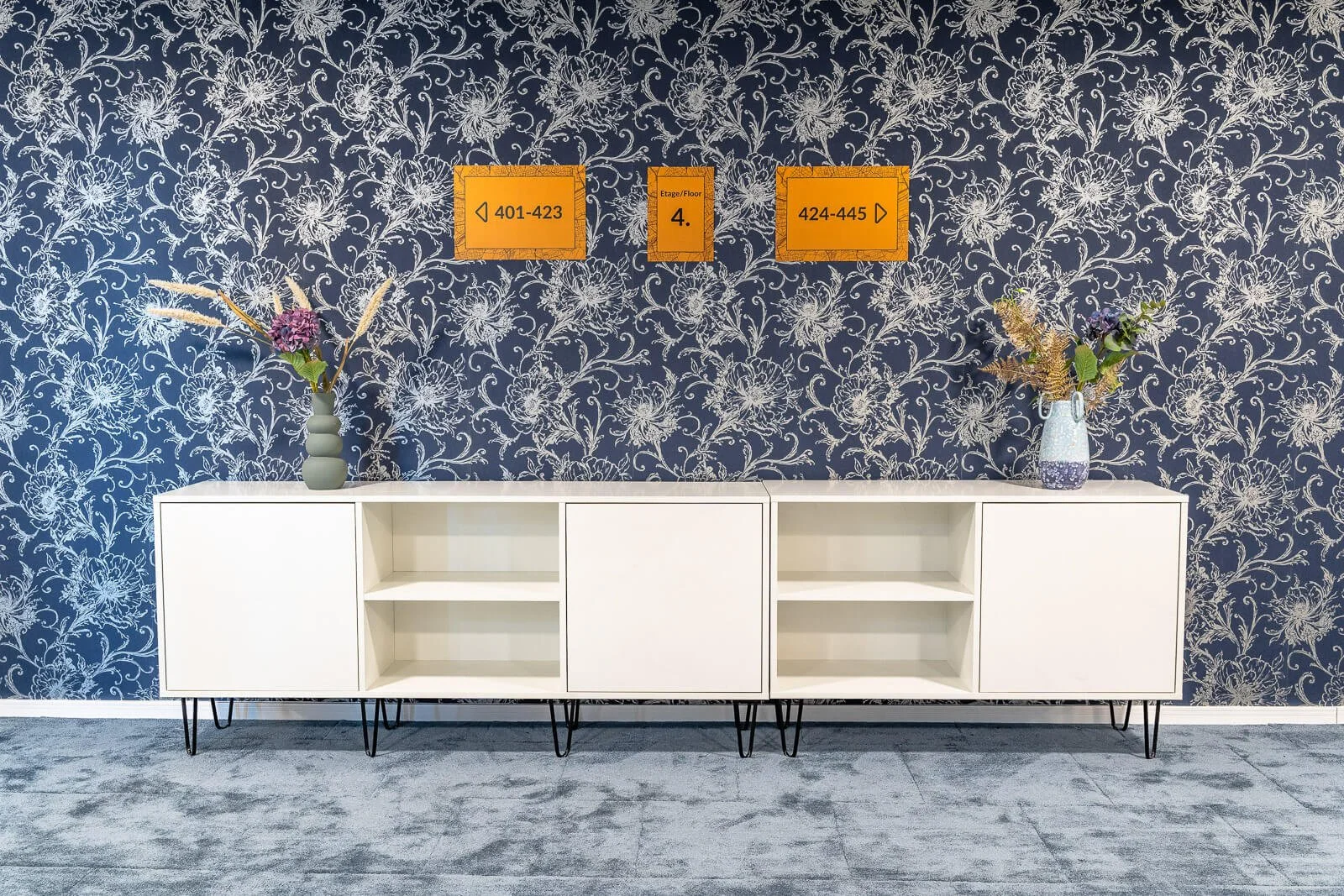 Moderner Hotel-Flur mit dekorativer Tapete, Wegweisern und minimalistischen Möbeln.