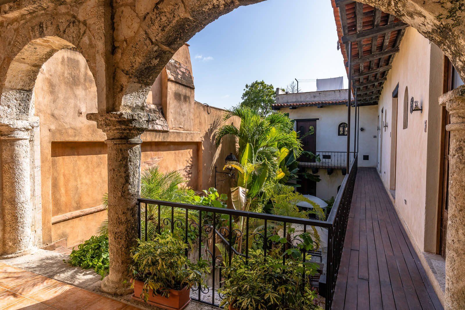 Historischer kolonialer Innenhofkorridor mit Pflanzen und Steinbögen in Santo Domingo.
