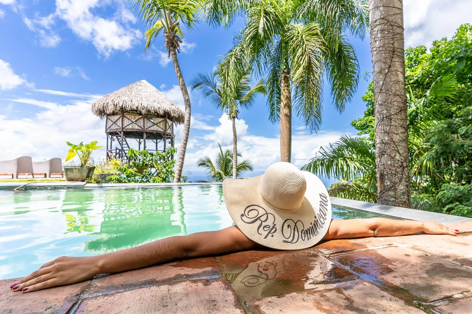 Gast entspannt am Pool eines Boutique-Hotels unter Palmen, Sommersonne und tropische Atmosphäre.