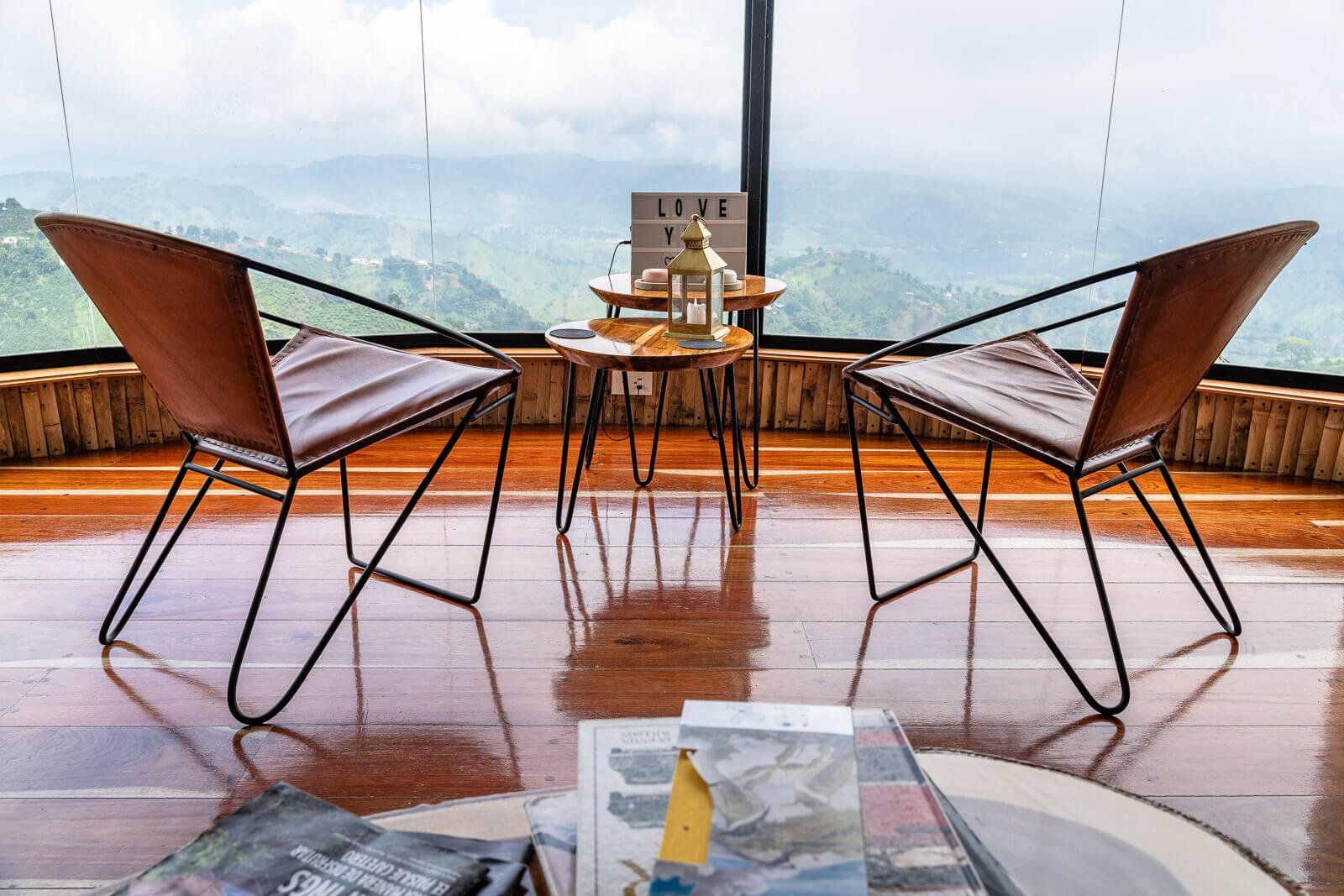 Sitzbereich mit zwei Lederstühlen und Bergpanorama in einem luxuriösen Glamping-Loft auf einer Kaffeeplantage in Kolumbien.