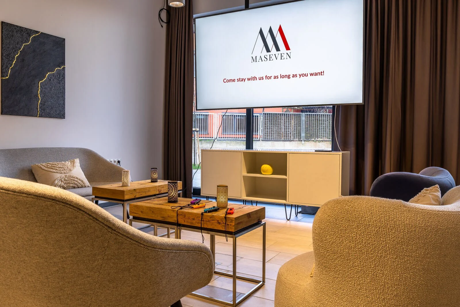 Moderne Hotel-Lobby mit hellen Lounge-Möbeln und großem Screen im urbanen Design.