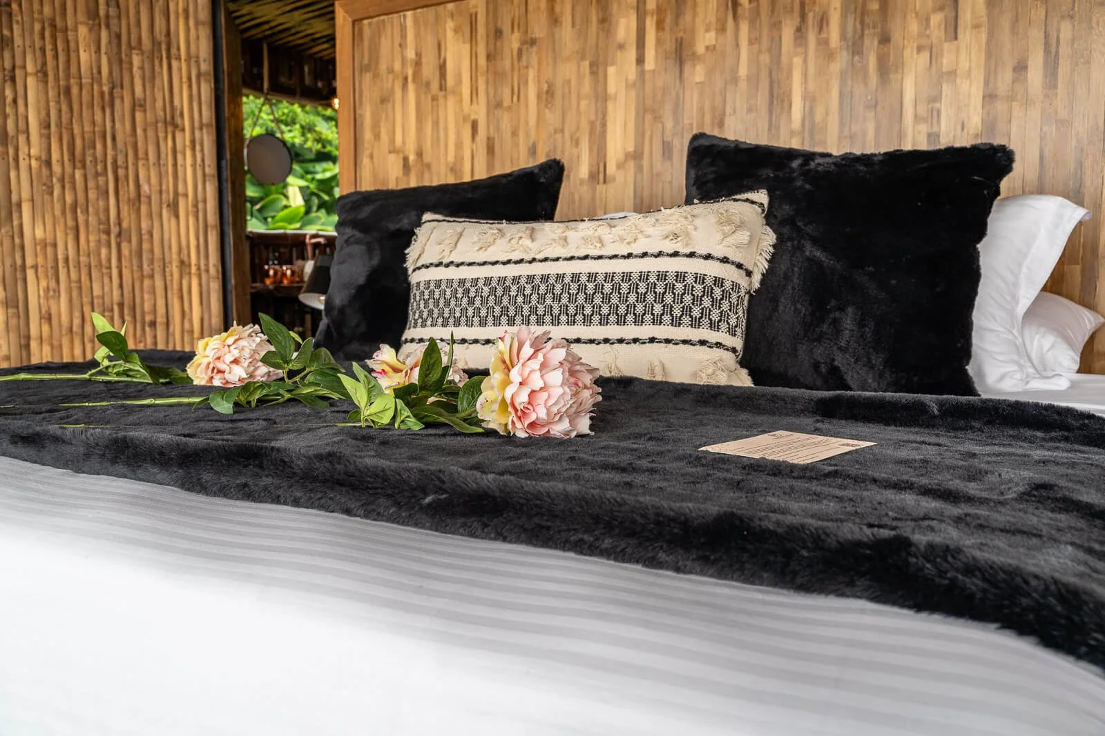 Detailaufnahme eines mit Blumen dekorierten Bettes im hochwertigen Glamping-Bungalow aus Bambus.