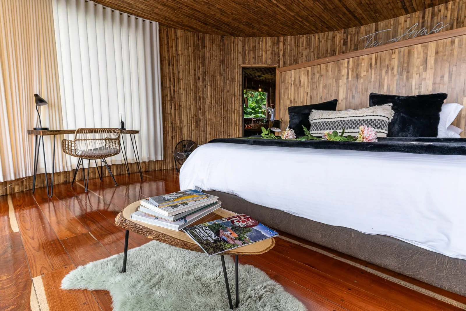 Großzügige Glamping-Suite aus Holz in Manizales mit Kingsize-Bett, Schreibtisch und Wohnbereich.