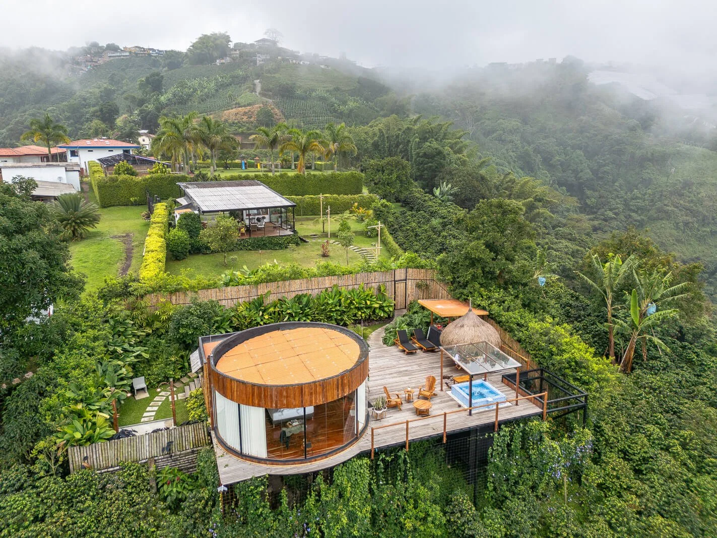 Luftaufnahme eines luxuriösen Glampings bei Manizales in Kolumbien, umgeben von Nebel und üppigem Grün.