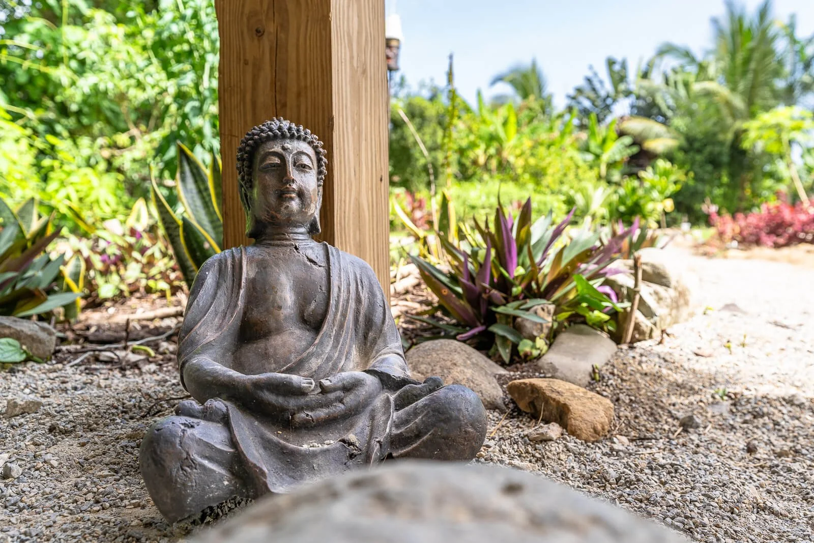 Buddha-Skulptur im tropischen Garten einer Eco-Lodge – Design-Detail mit naturverbundener Atmosphäre.