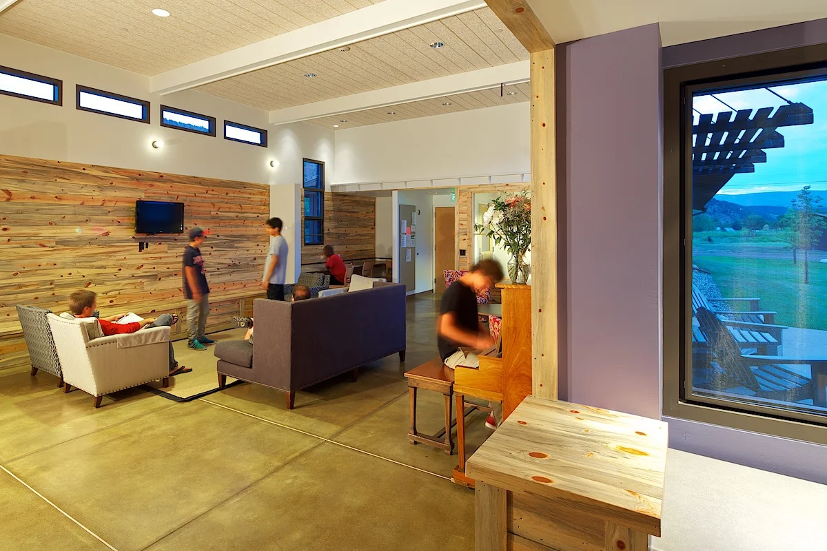 Students hang out and play the piano in the north dorm's common room