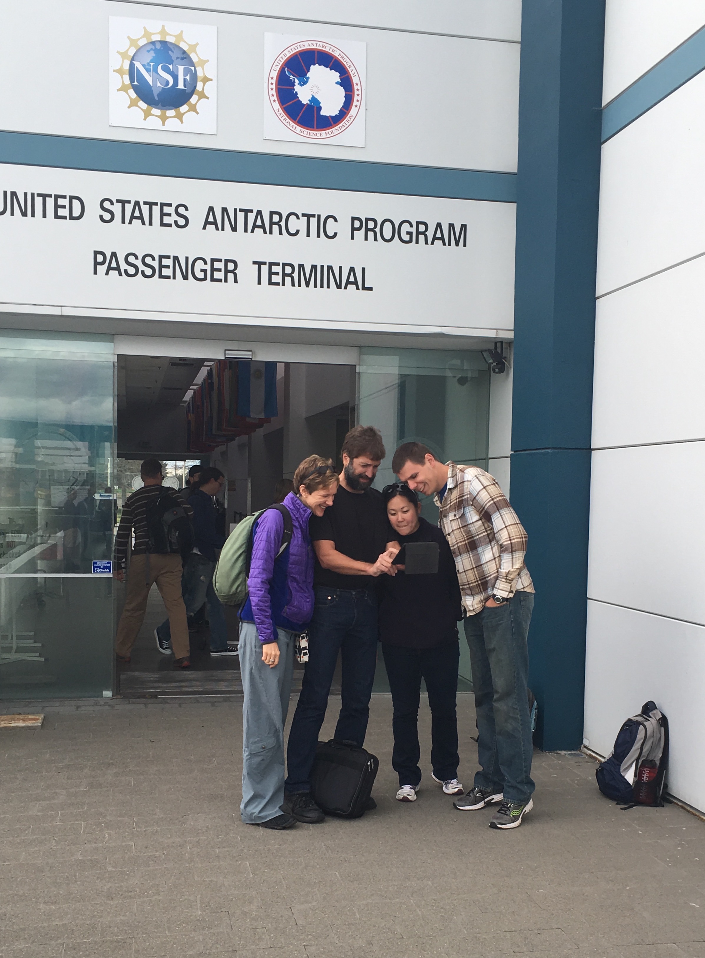 Amy, Bret, Caitlin, and Steve gathering around an iPad at the USAP Passenger Terminal in Christchurch. When we arrive at McMurdo we'll lose all smartphone and handheld connectivity. 