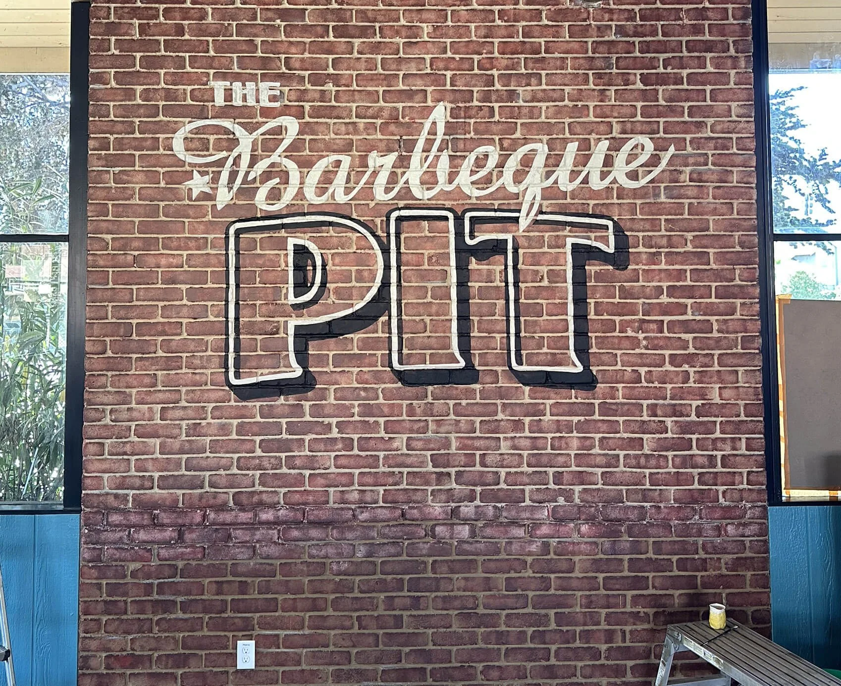BBQ Pit dining room logo on brick wall 2025 