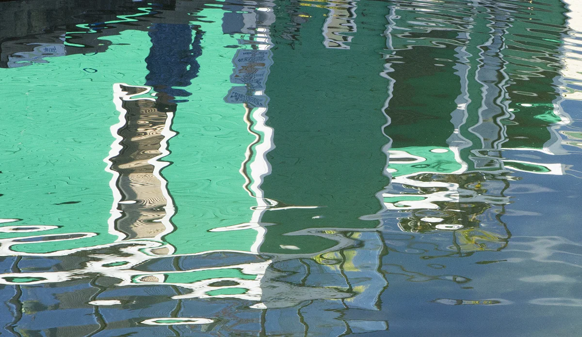 Recently I had a chance to be in Victoria, British Columbia. On their Fishermen's Wharf, there are three piers along which there are floating houses. Not house boats, the sign told us, but floating houses. House boats can go places, but floating houses will stay right where they are floating by the pier to which they are tied. The houses were painted bright colors. What I loved most about the floating houses was the wonderful reflections they made on the water and the way the waves distorted the reflections turning them into abstract images. This one is one of my favorites. 