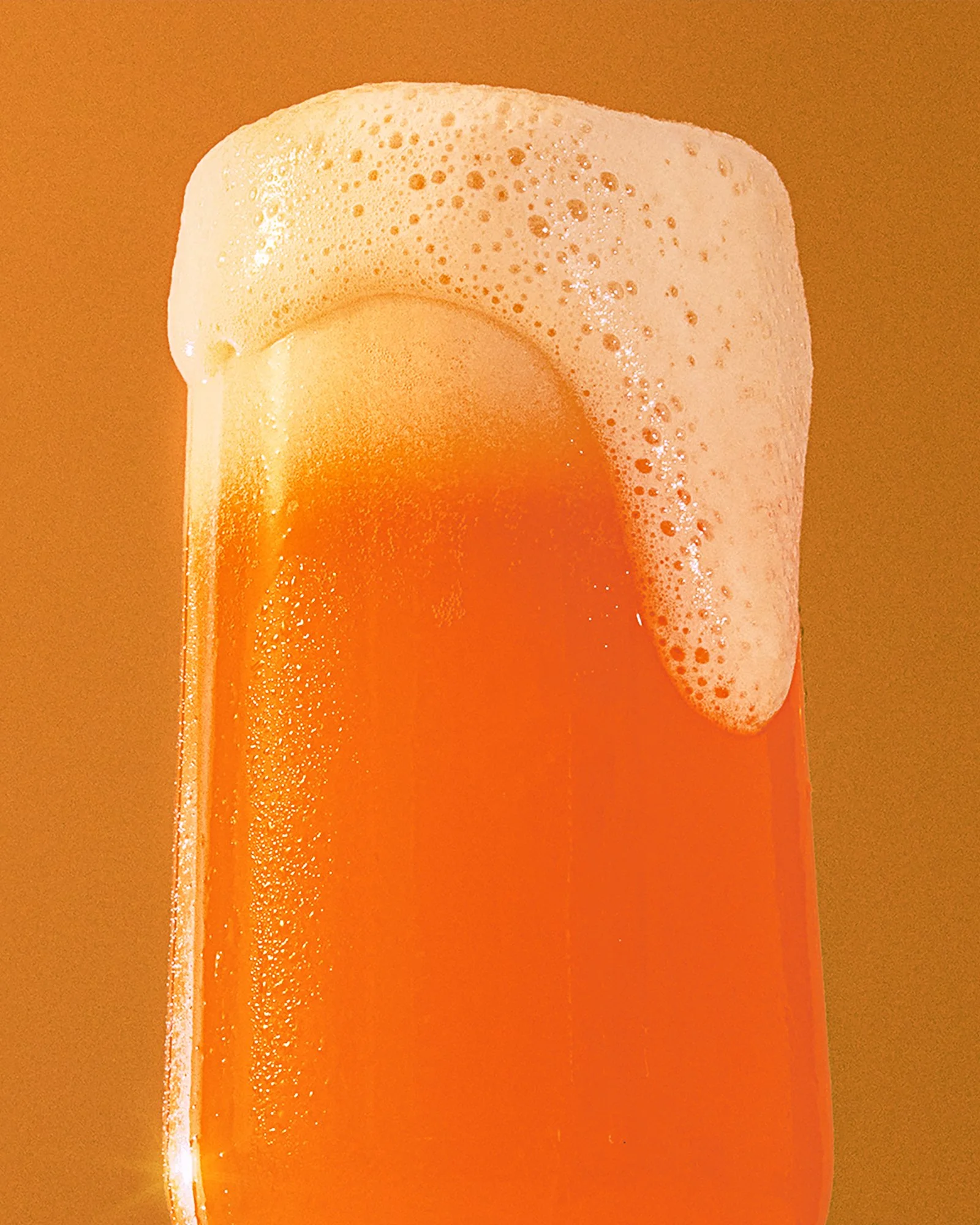 a photo of a glass of beer with foam pouring over / shot by Commercial beverage photographer Ali Redmond