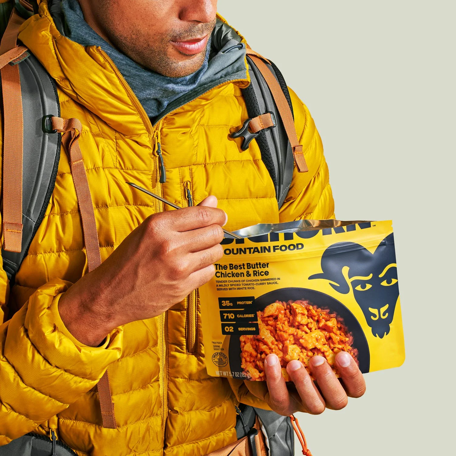 Commercial photography of a man eating out of a dehydrated hiking meal