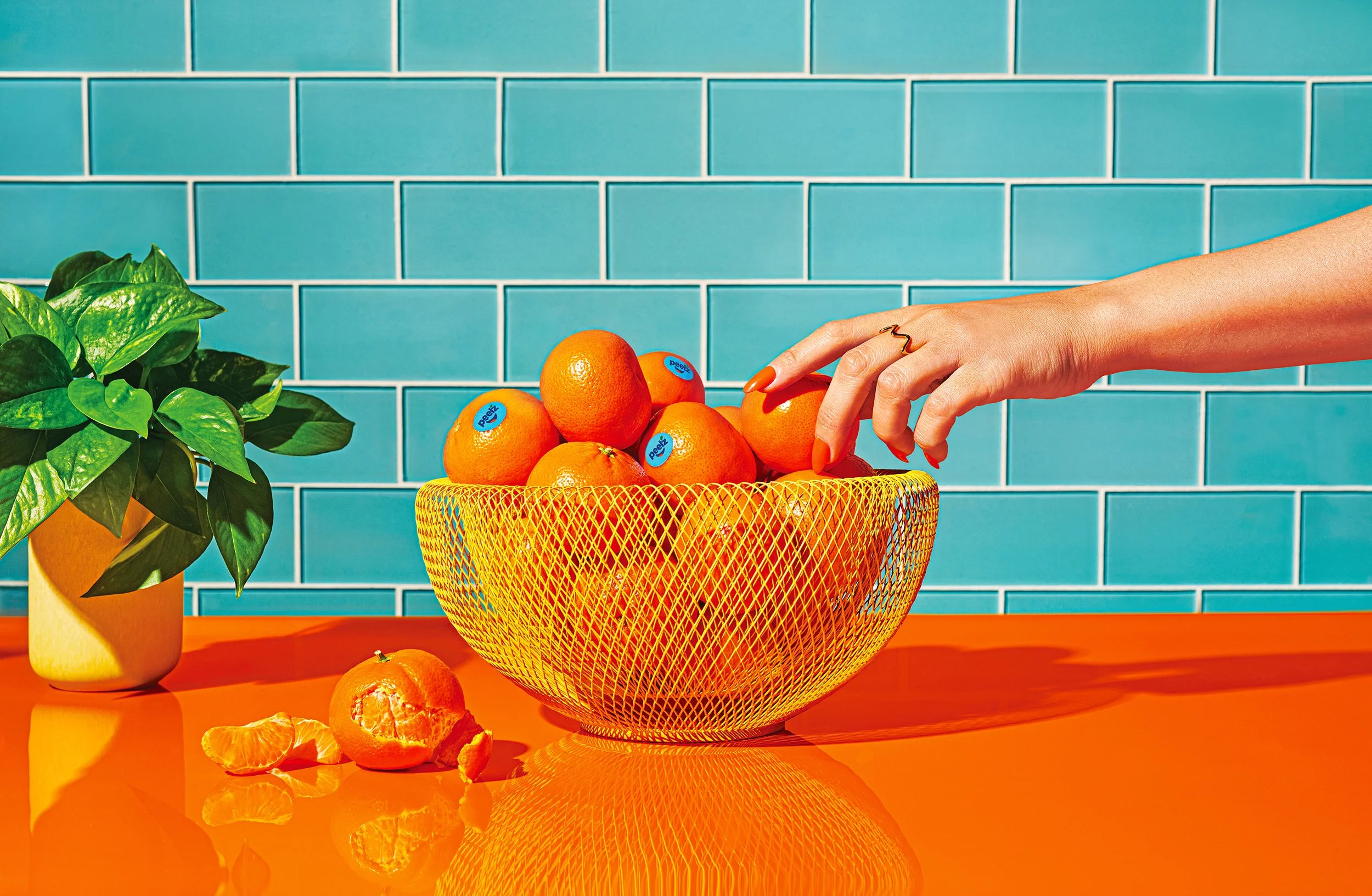 Commercial photography of a hand reaching in to a bowl of oranges
