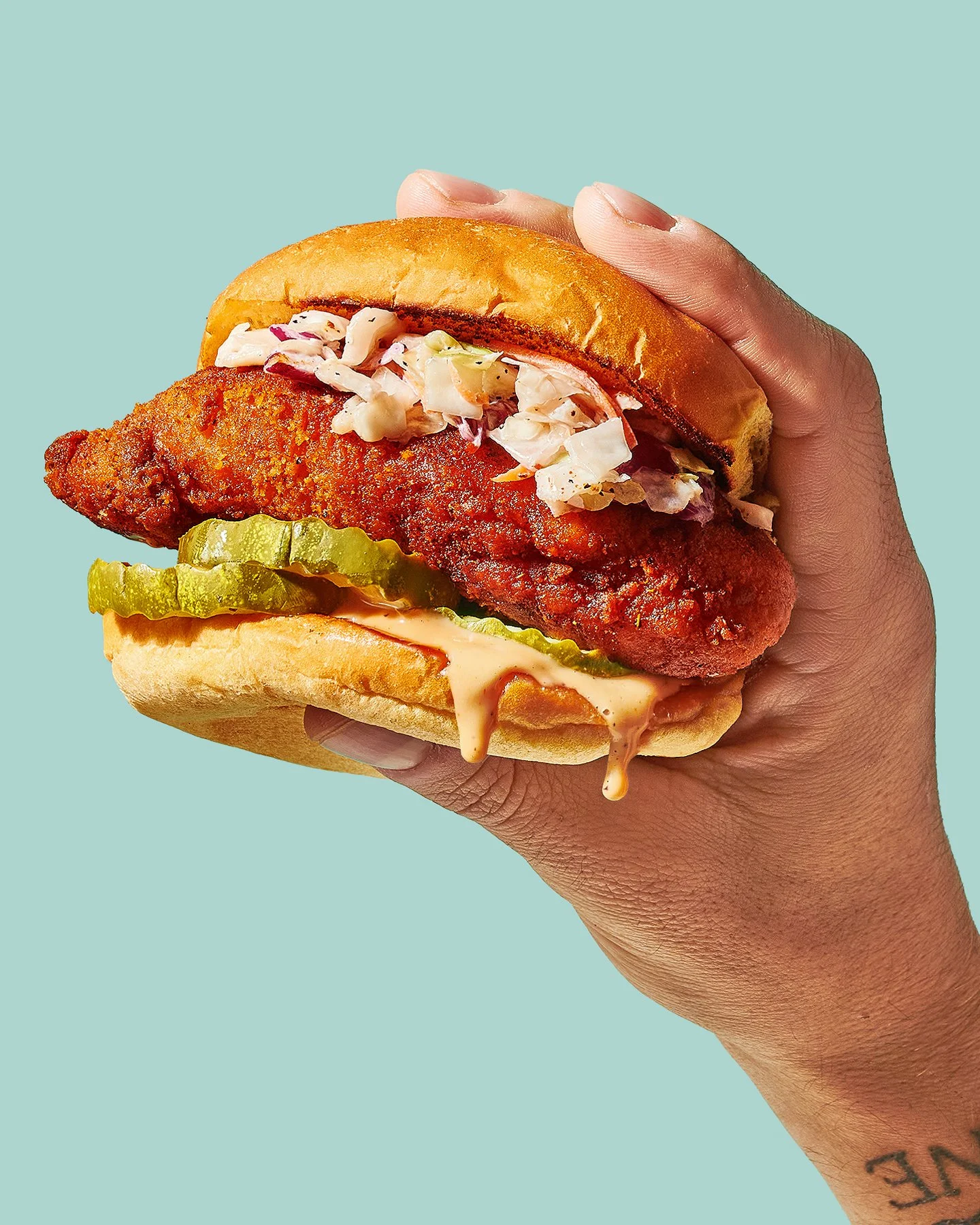 Commercial photography of a hand holding a nashville hot chicken sandwich