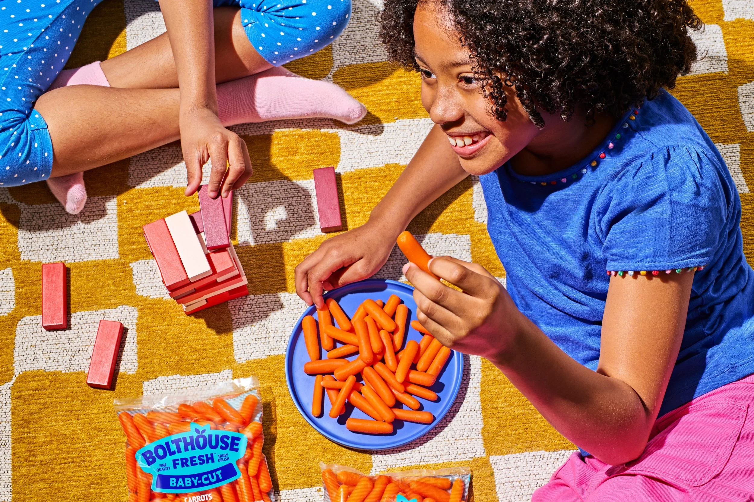 Commercial photography of a girl sitting eating carrots and playing games