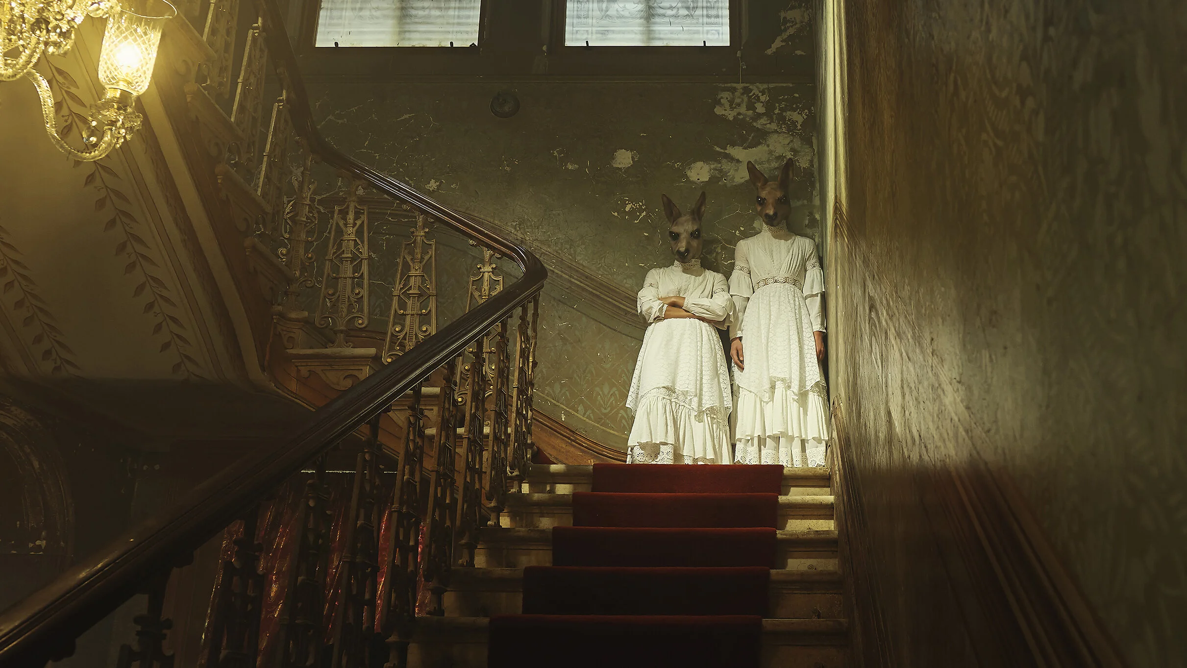 Two humanoid figures with dog heads wearing white dresses standing at the top of a staircase in an old, dimly lit building with peeling walls and ornate metal railings.
