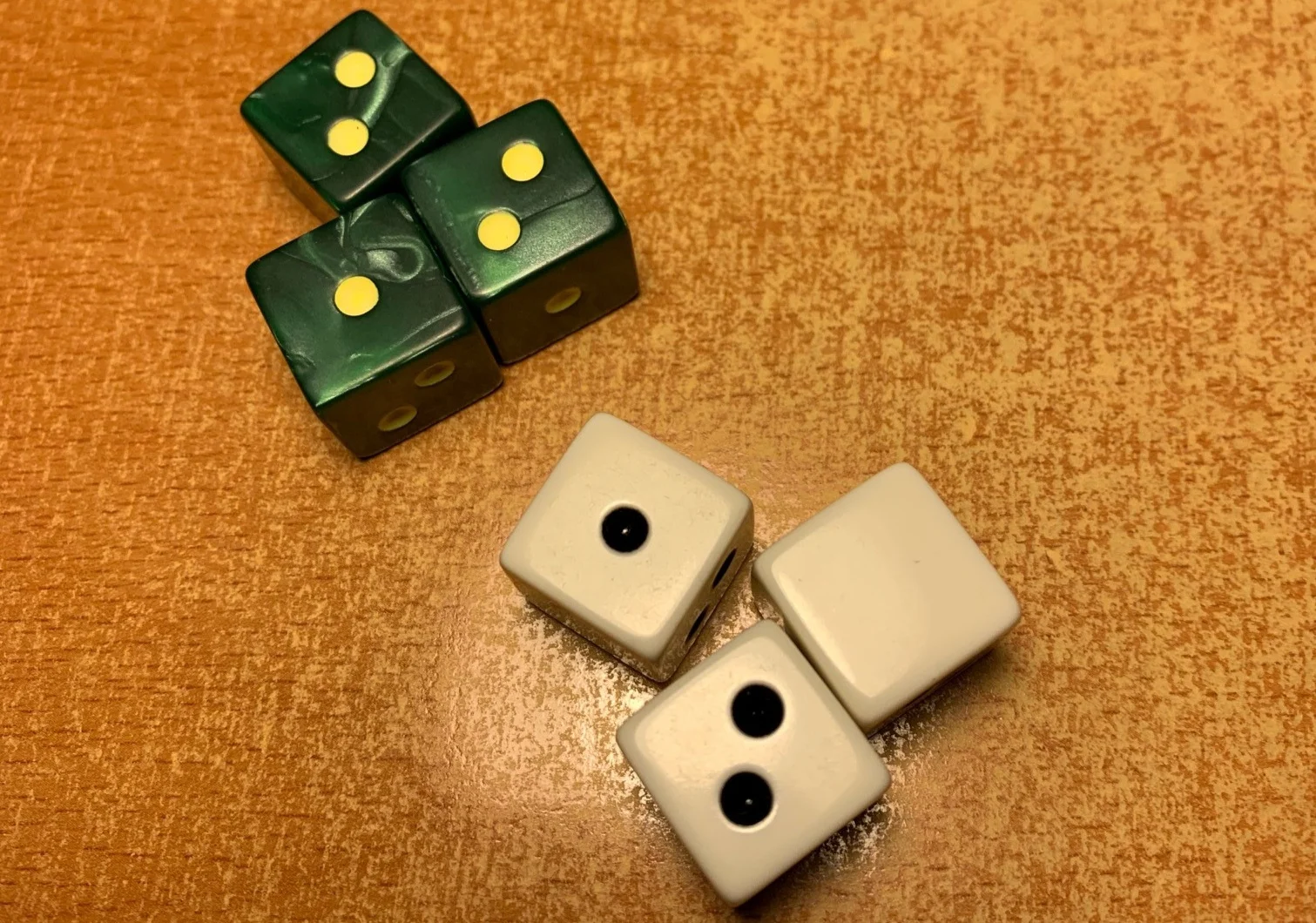 Premium pearlescent green die with yellow pips vs. the standard bones