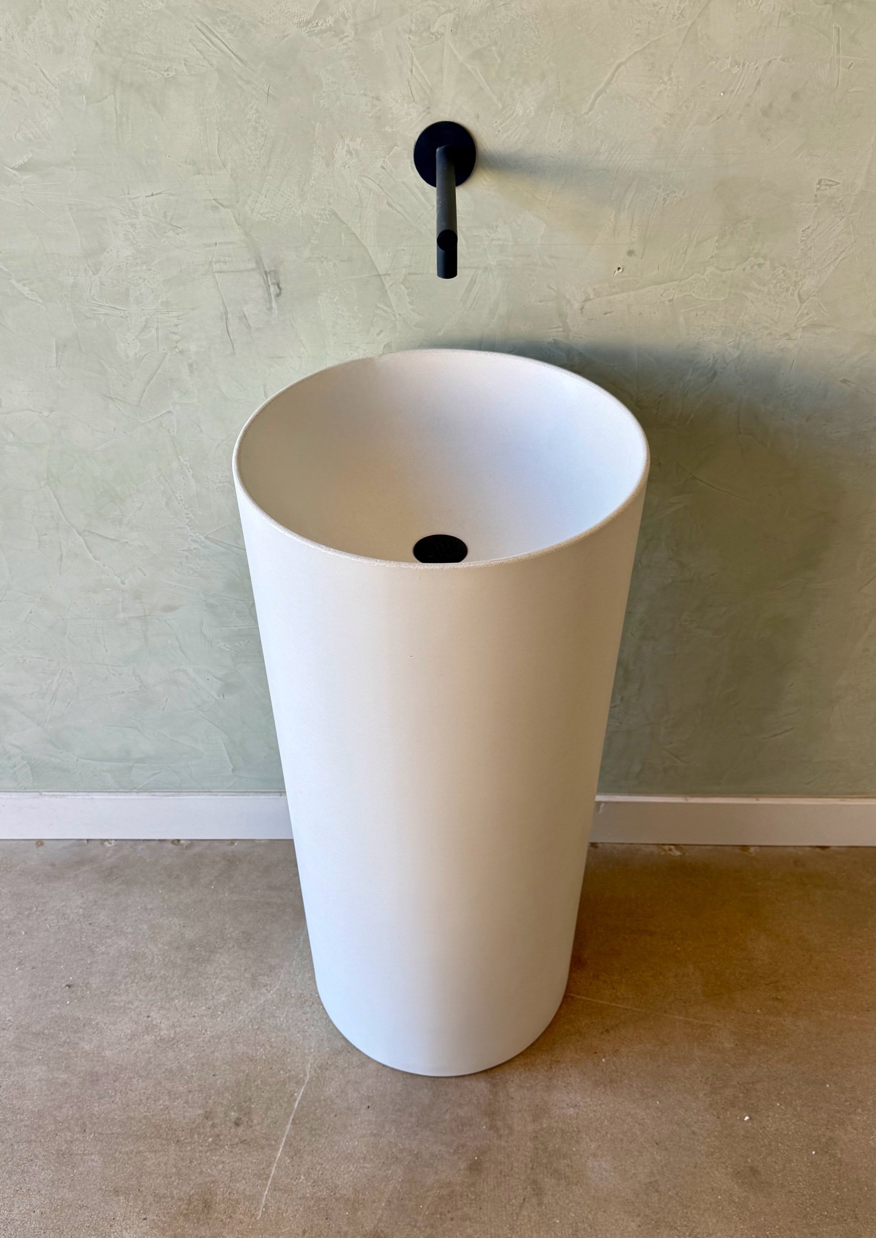 Overhead view of a white round concrete pedestal sink with smooth matte finish and seamless basin