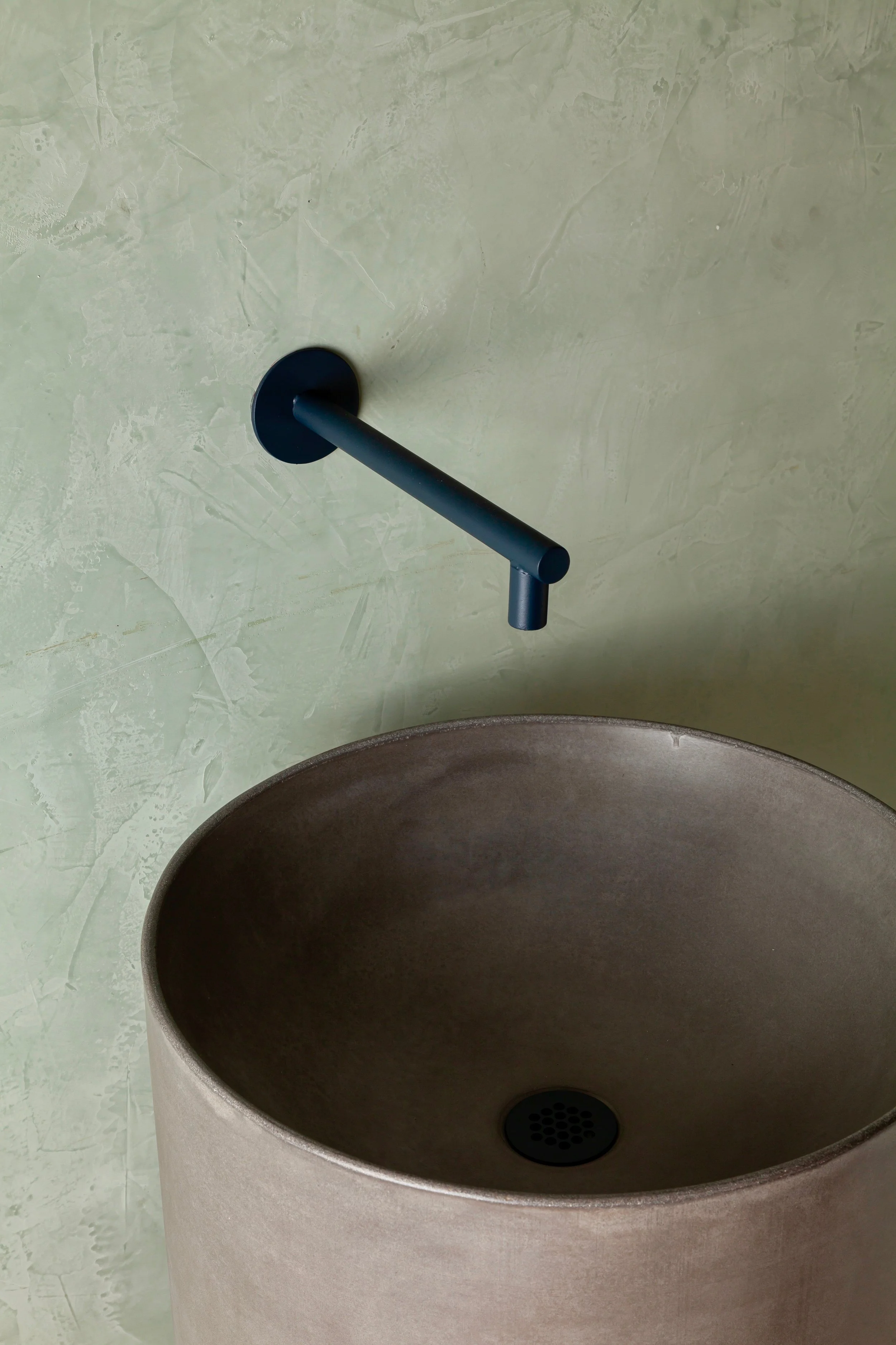 Close-up of round basin on dark grey luxury concrete pedestal sink with smooth handcrafted finish