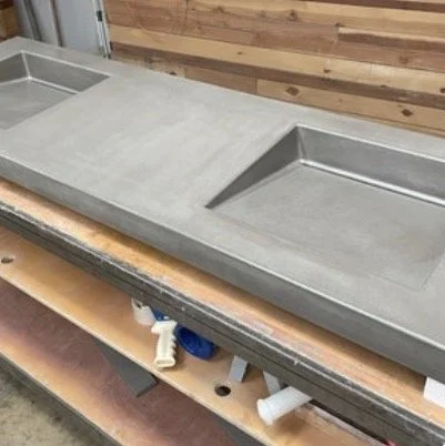 Front right view of grey Double Ramp concrete sink, slatted wood wall background, handmade slot drain basin