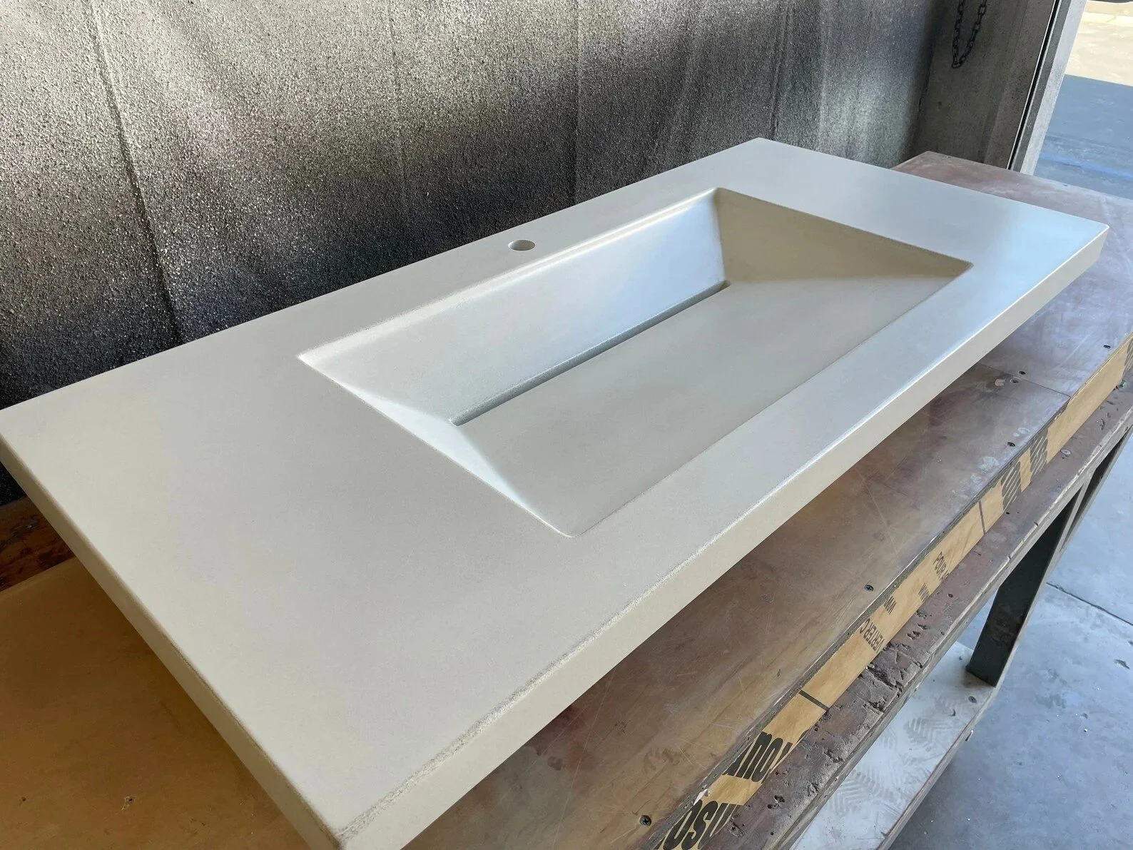 Left-side angled view of a handmade concrete sink in natural finish, showcasing its minimalist design and smooth surface
