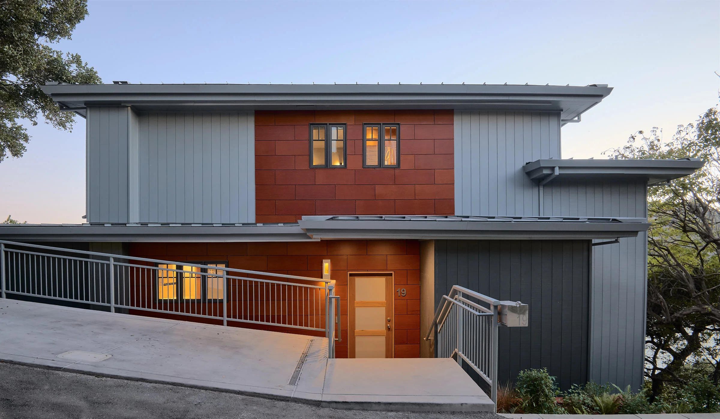 My solution to give it more street appeal, was to add a focus to the second floor and make the windows symmetrical. Lights were added in the entry soffit, a new frosted glass entry door , a standing seam metal roof was added to replace the tar & gravel and a new "Parkflex" skin was added for visual interest and punch.