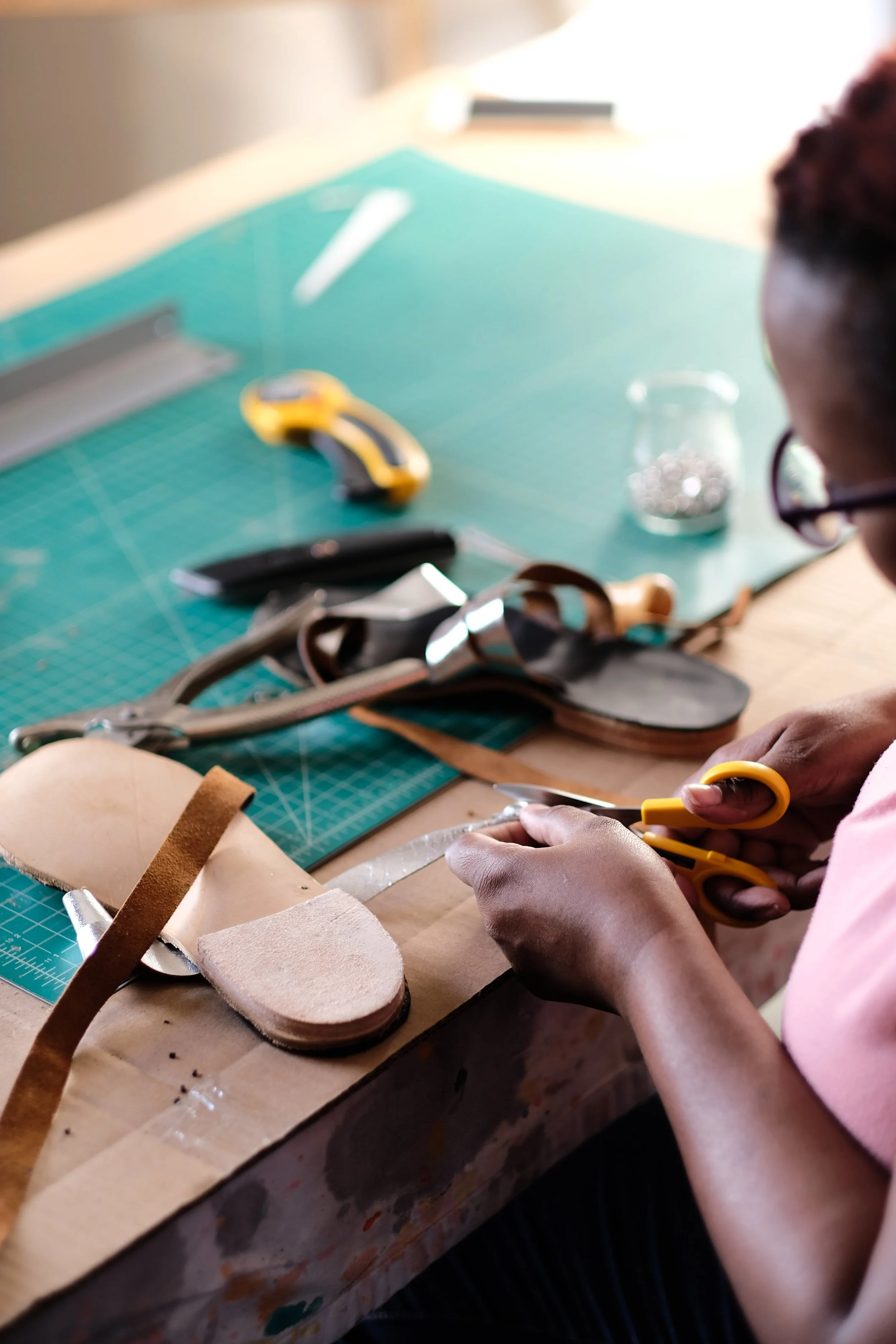 Using rulers, strap-cutters, serrated scissors and cardboard patterns, you'll cut out your leather soles and straps...