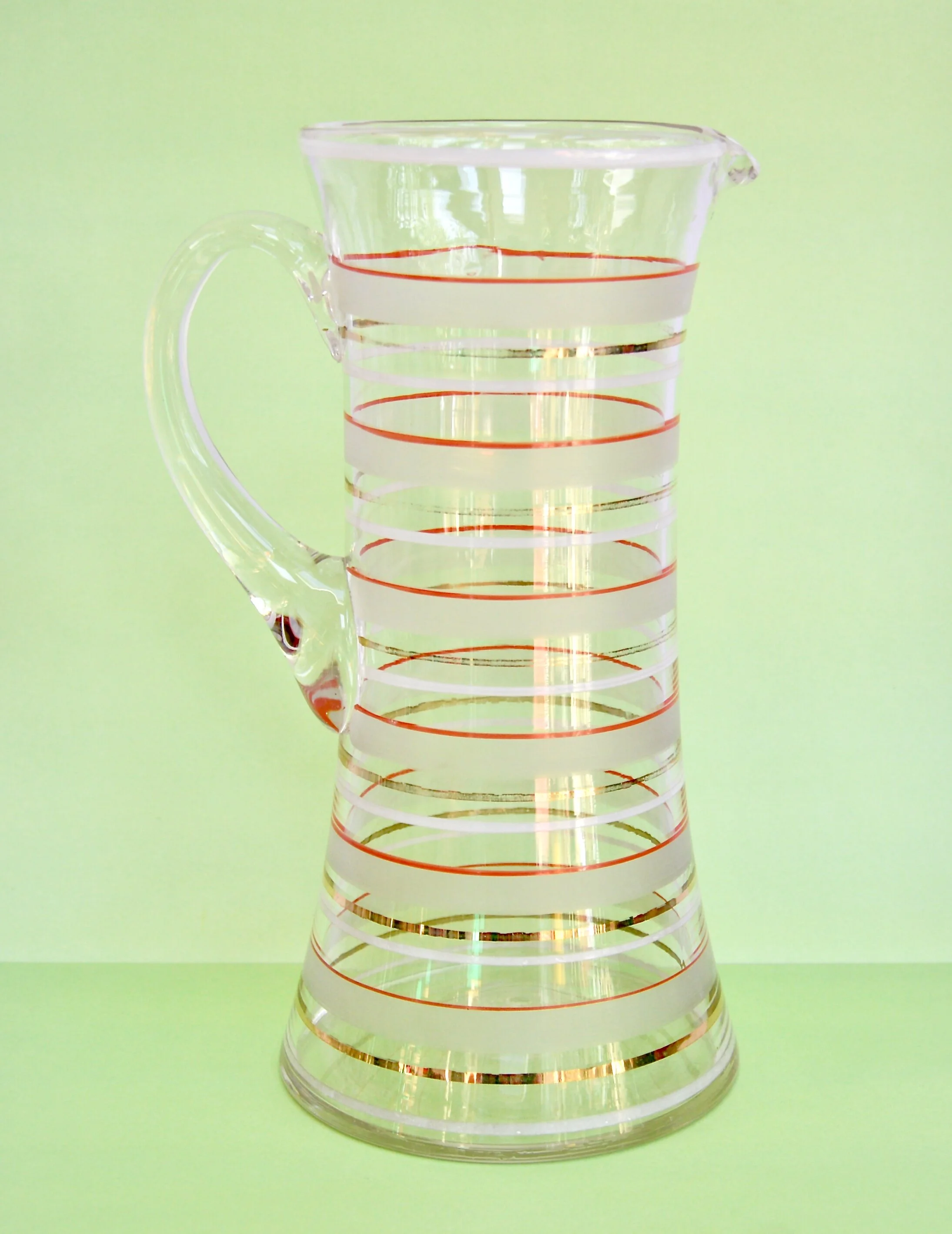 1930s hourglass pitcher with red, gold and frosted banding and applied glass handle.