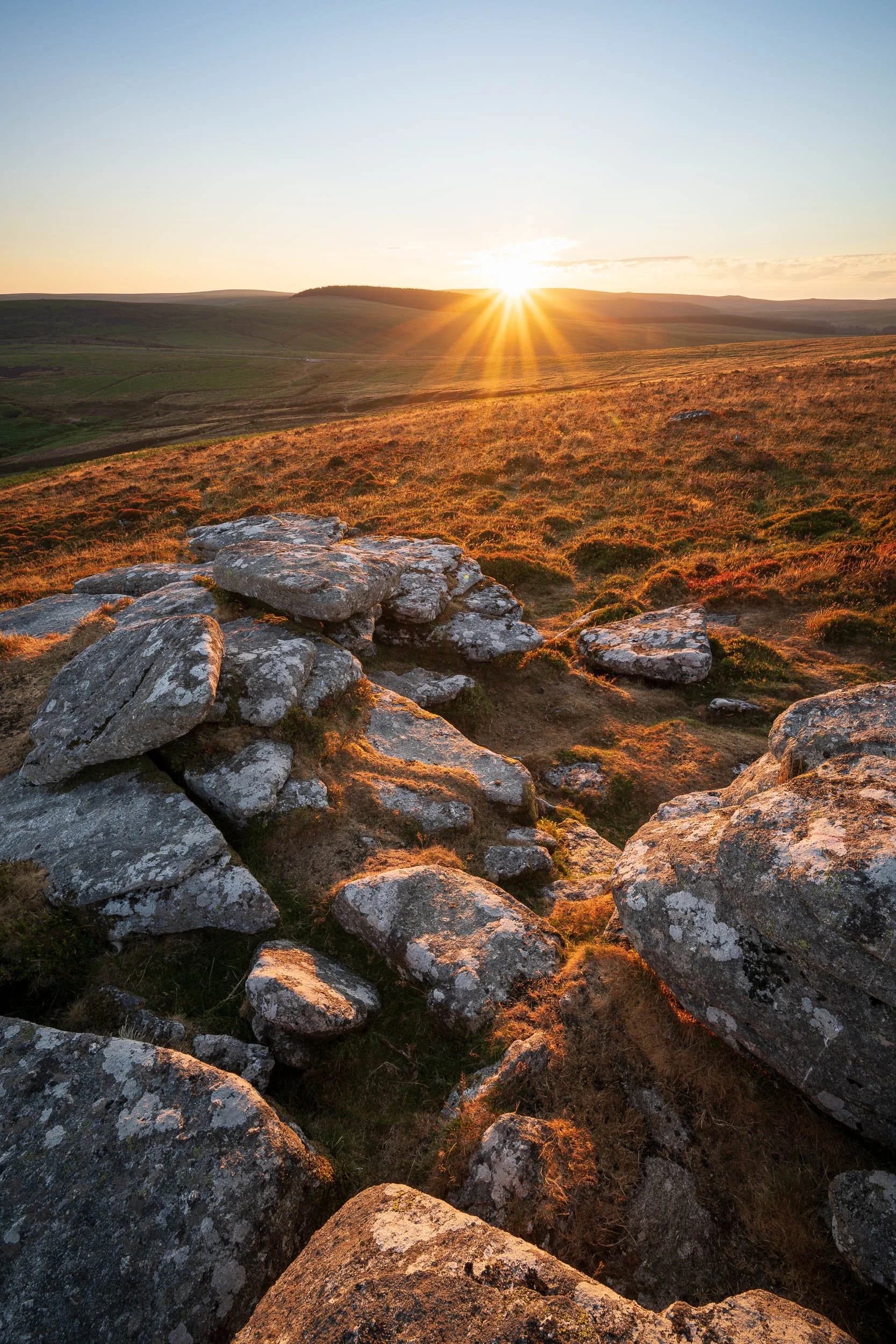 A landscape photograph of Birch Tor on Dartmoor National Park looking into the setting sun.