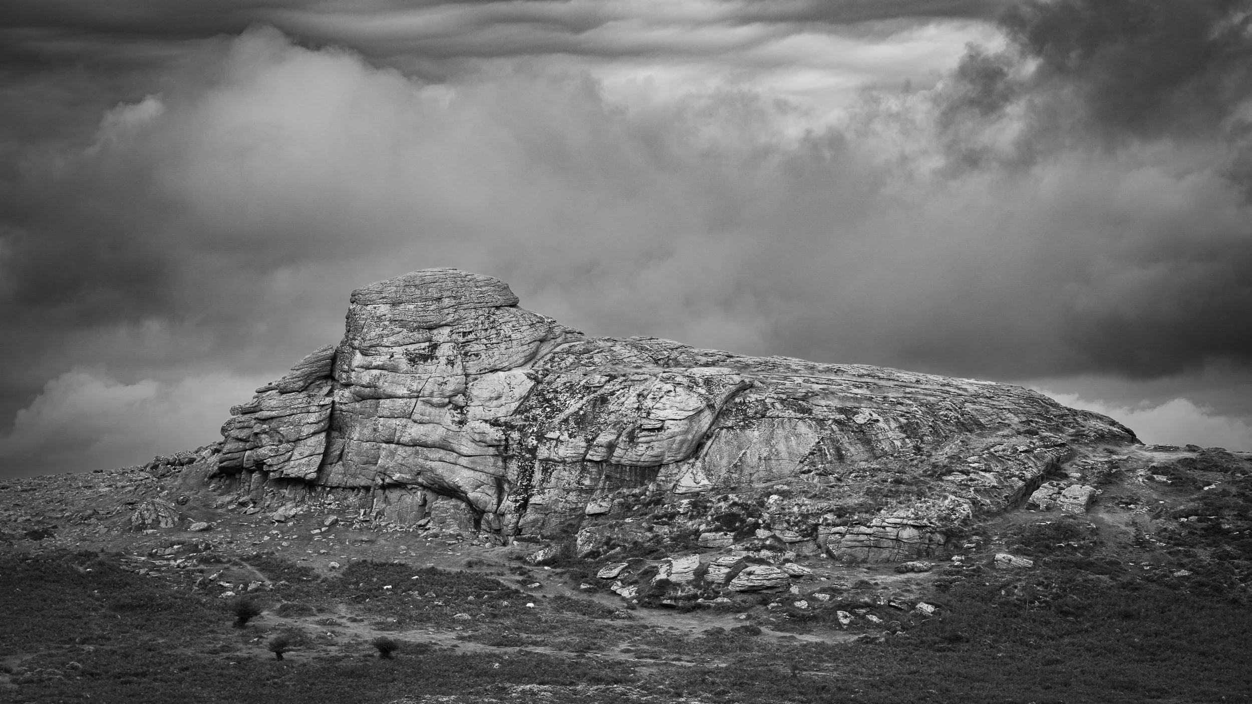 A black and white photograph of Haytor on Dartmoor in stormy conditions.
