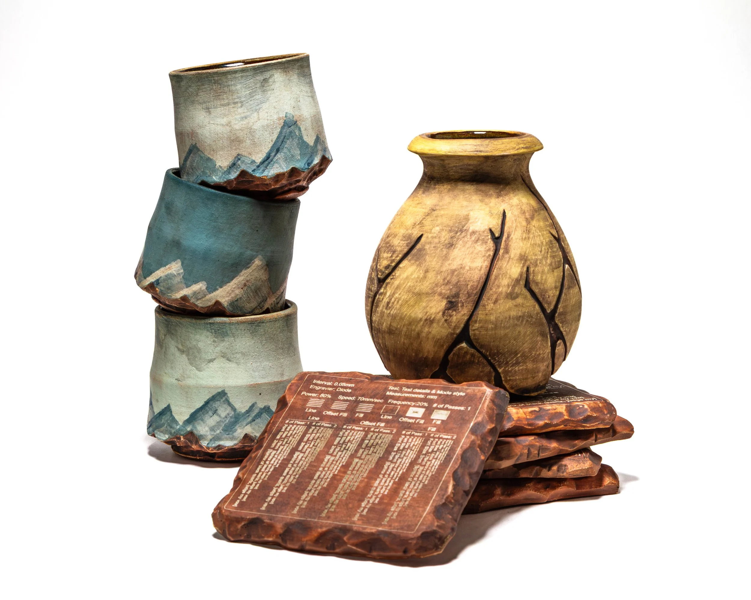 Various handcrafted pottery and glazed ceramic vases displayed on a table, with informational tags in front.
