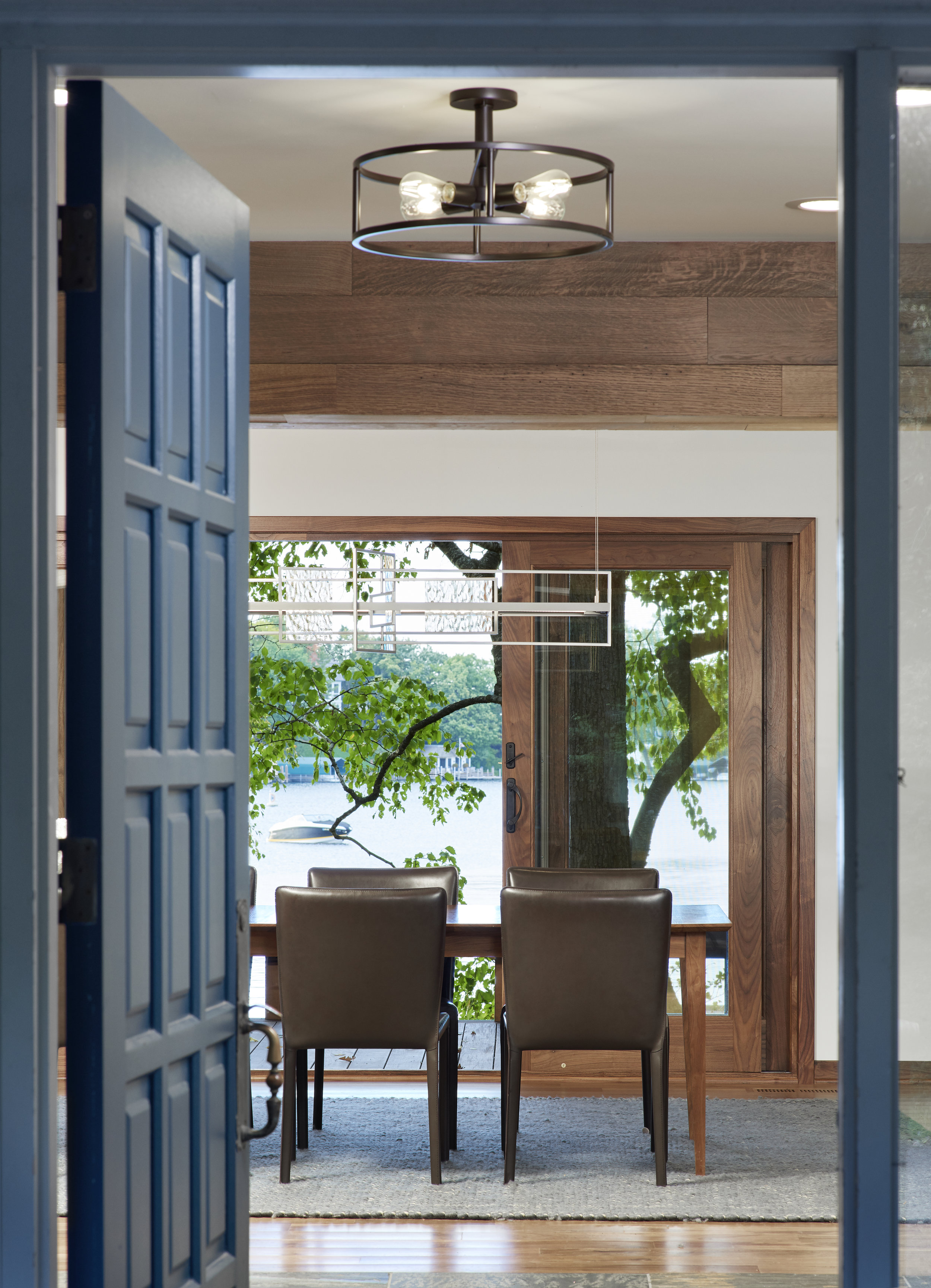 Blue interior door opens to dining room designed by designed by NewStudio Architecture with Lake Minnetonka view.