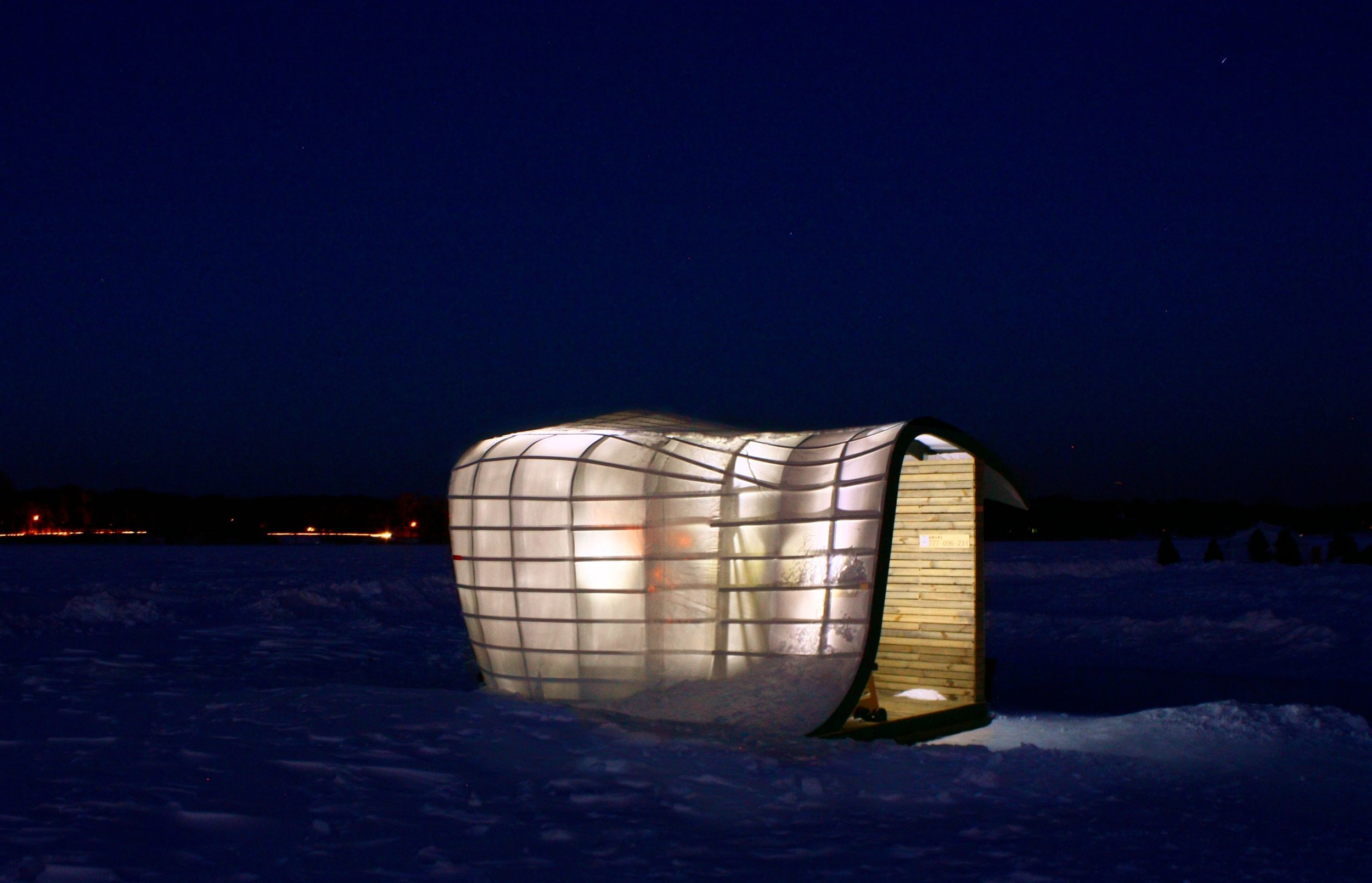 Nighttime exterior of lit-up art shanty designed by NewStudio Architecture