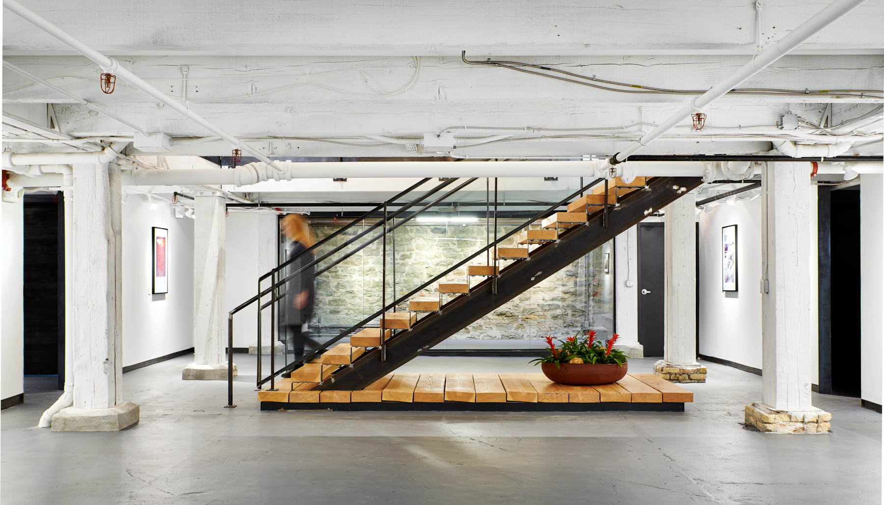 A custom steel and timber grand stair leads down to NewStudio Gallery at NewStudio Architecture's Saint Paul, Minnesota office.