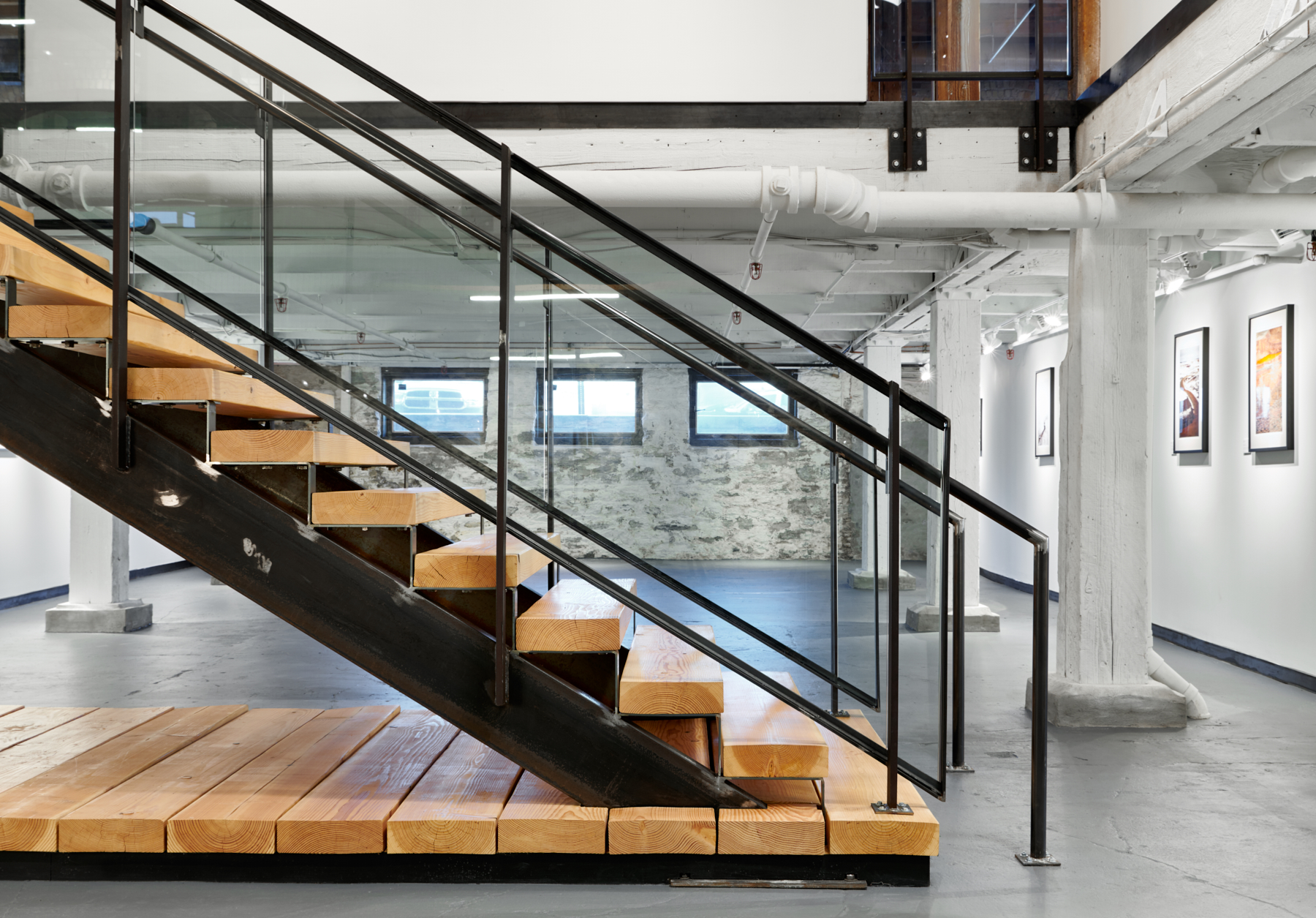 A custom steel and timber grand stair leads down to NewStudio Gallery at NewStudio Architecture's Saint Paul, Minnesota office.