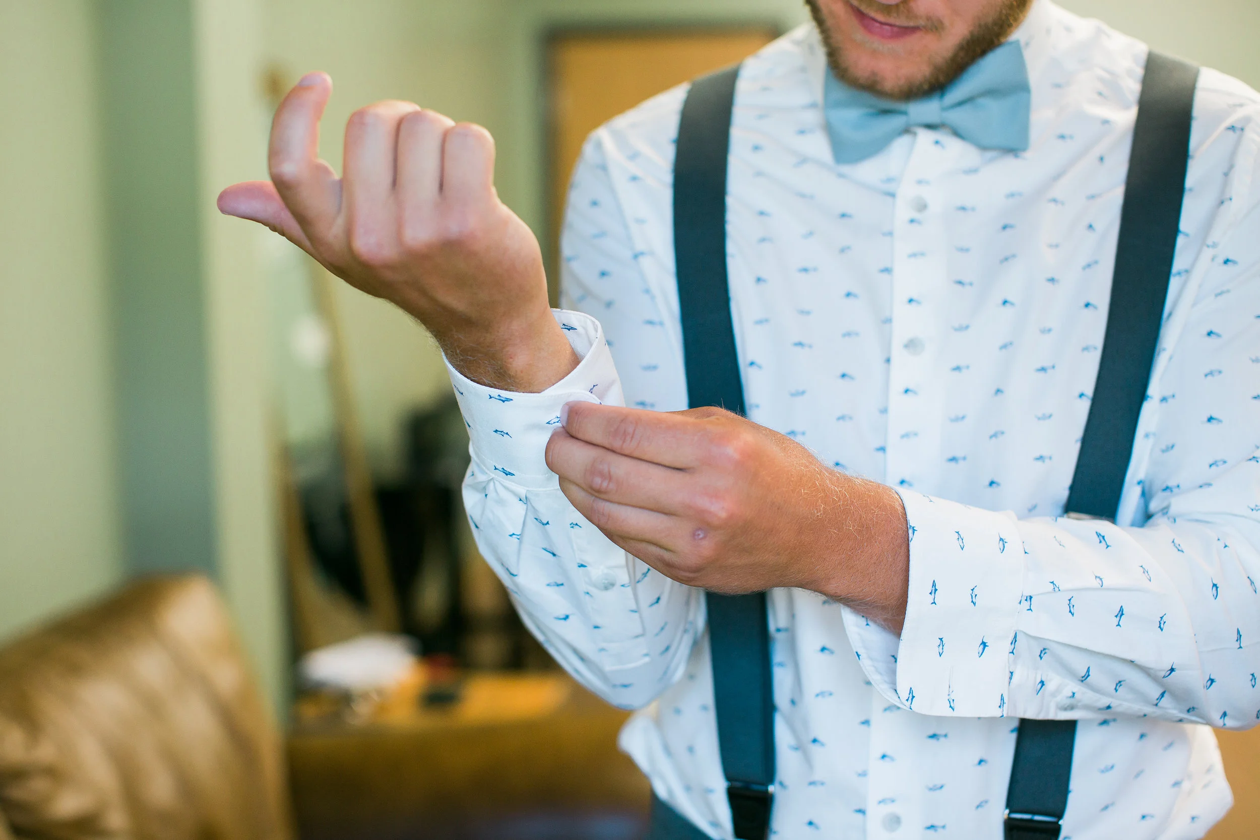 Groom getting ready for wedding day with suspenders at The Outpost Center in Chaska Minnesota in groom's rustic getting ready room