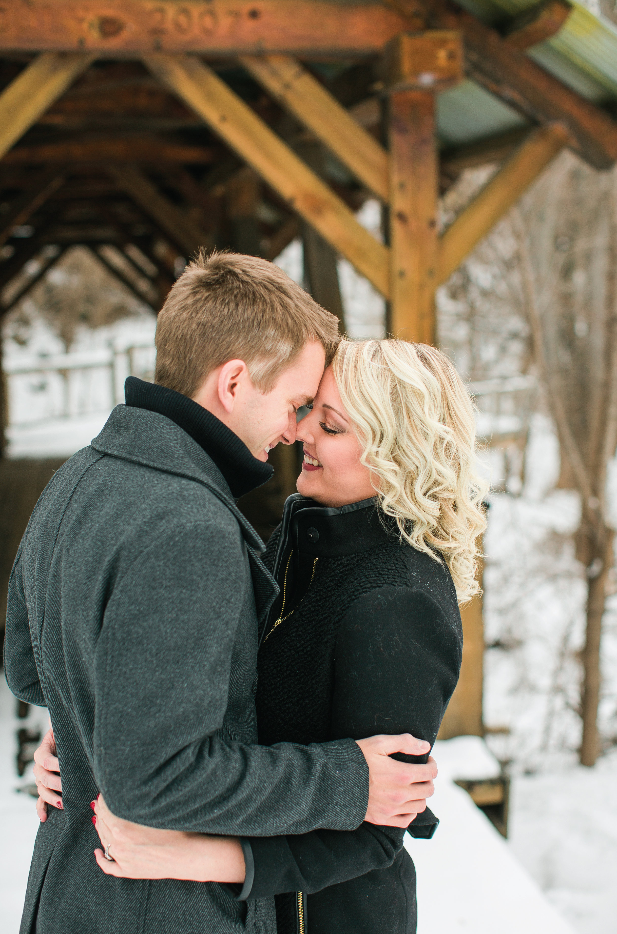 Minnesota engagement photos in Taylors Falls couple snuggling for kiss in winter coats
