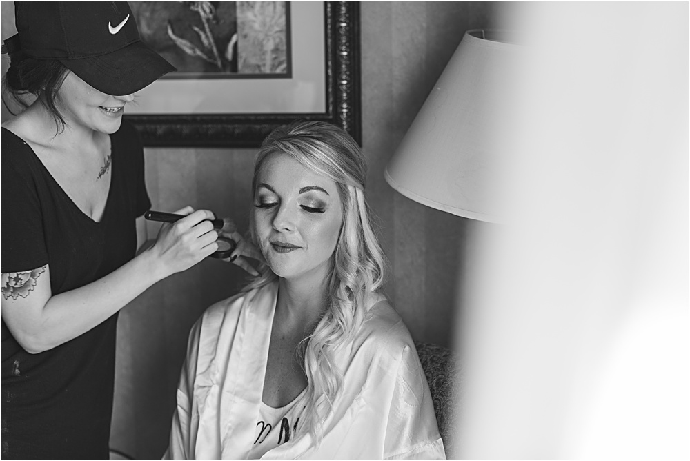 Minnesota summer wedding of bride getting makeup on in bridal robe in black and white