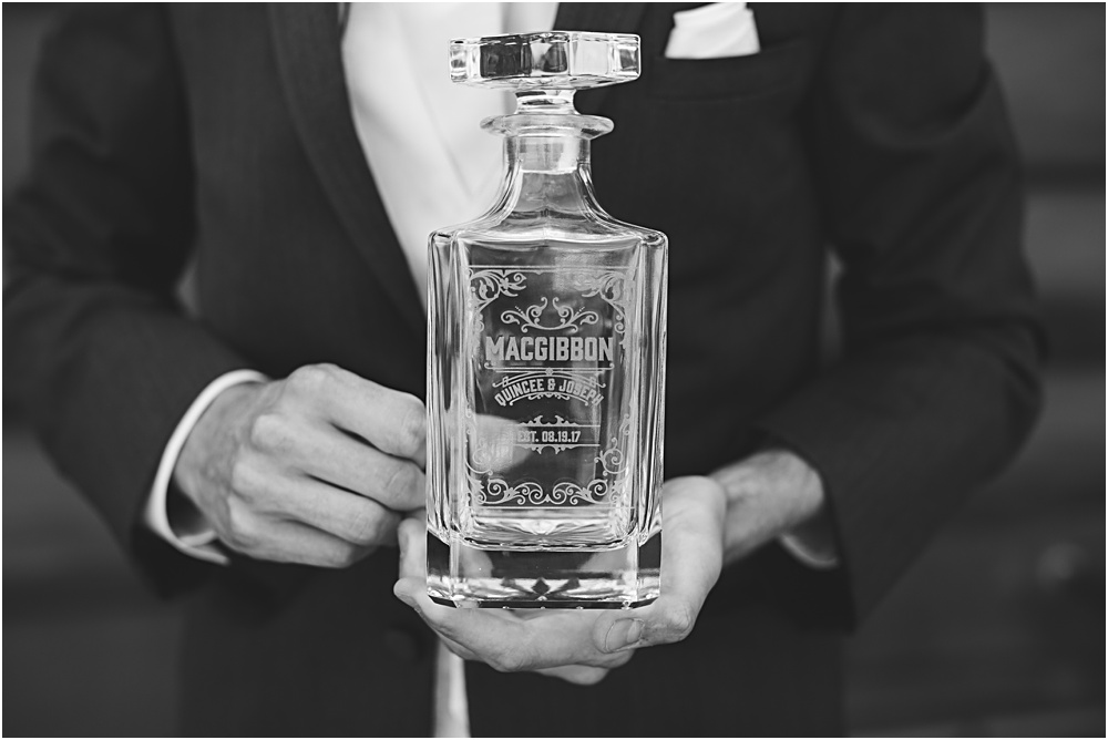 Groom reading letter from bride on wedding day during summer Minnesota wedding opens custom liquor bottle