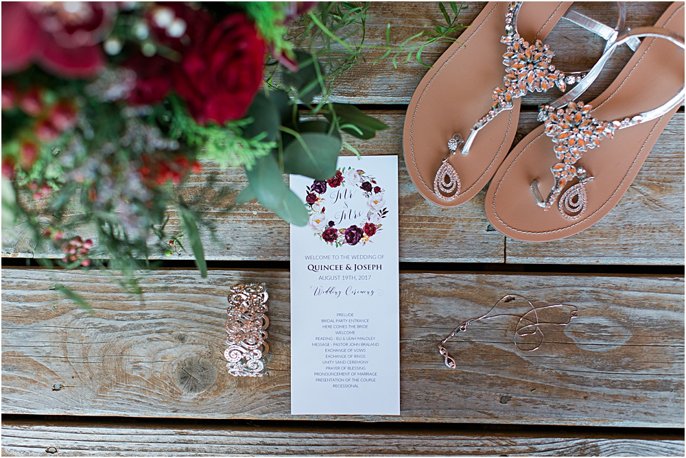 Minnesota summer wedding photo showing invitation, jewelry and shoes in burgundy wine color