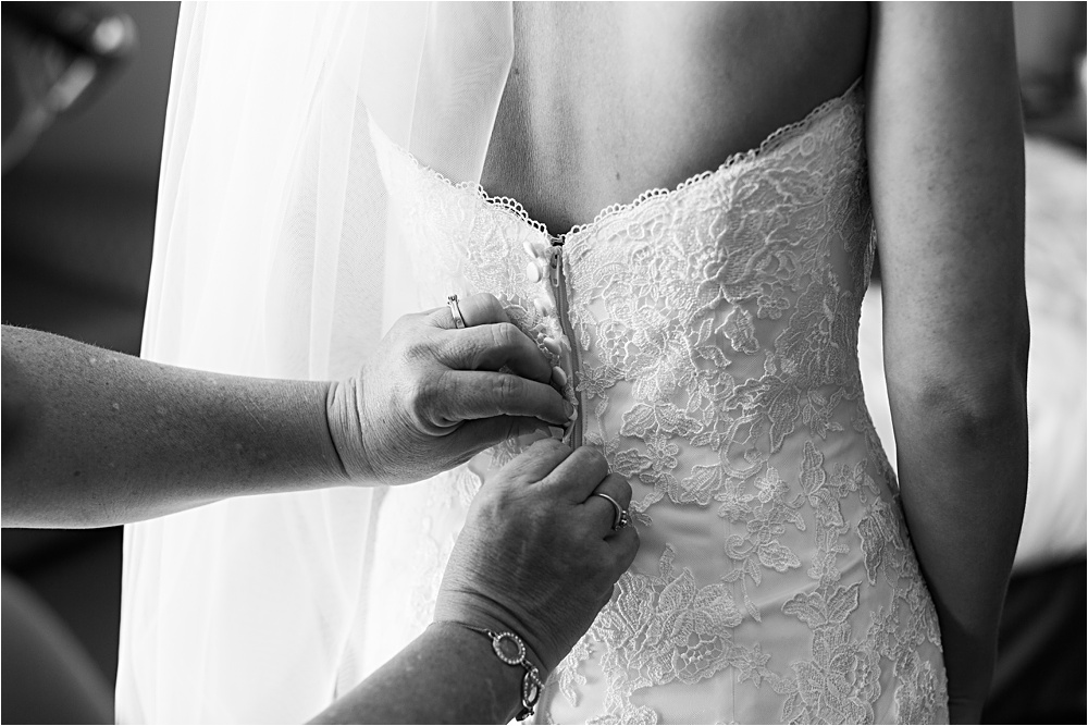 Bride putting on dress with mom's hands, touching moment at Minnesota summer wedding