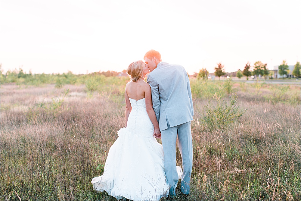 Bride and groom kissing in field during sunset of Minnesota summer wedding