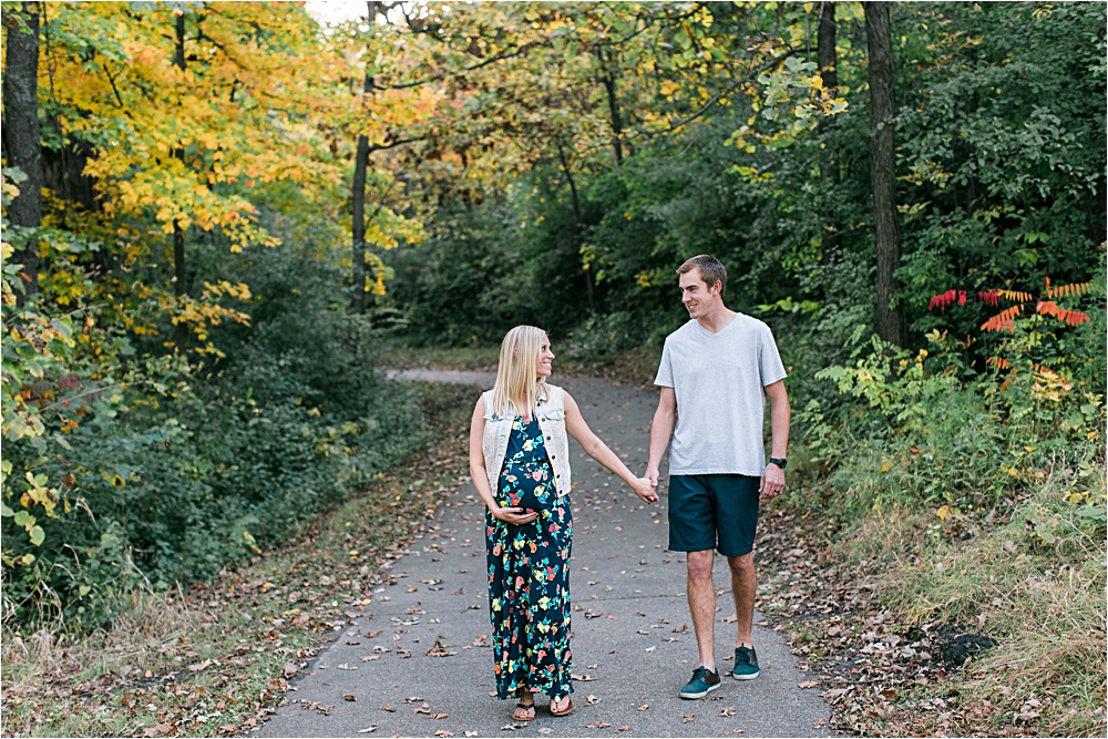 Husband and wife walking in fall maternity session in Minnesota