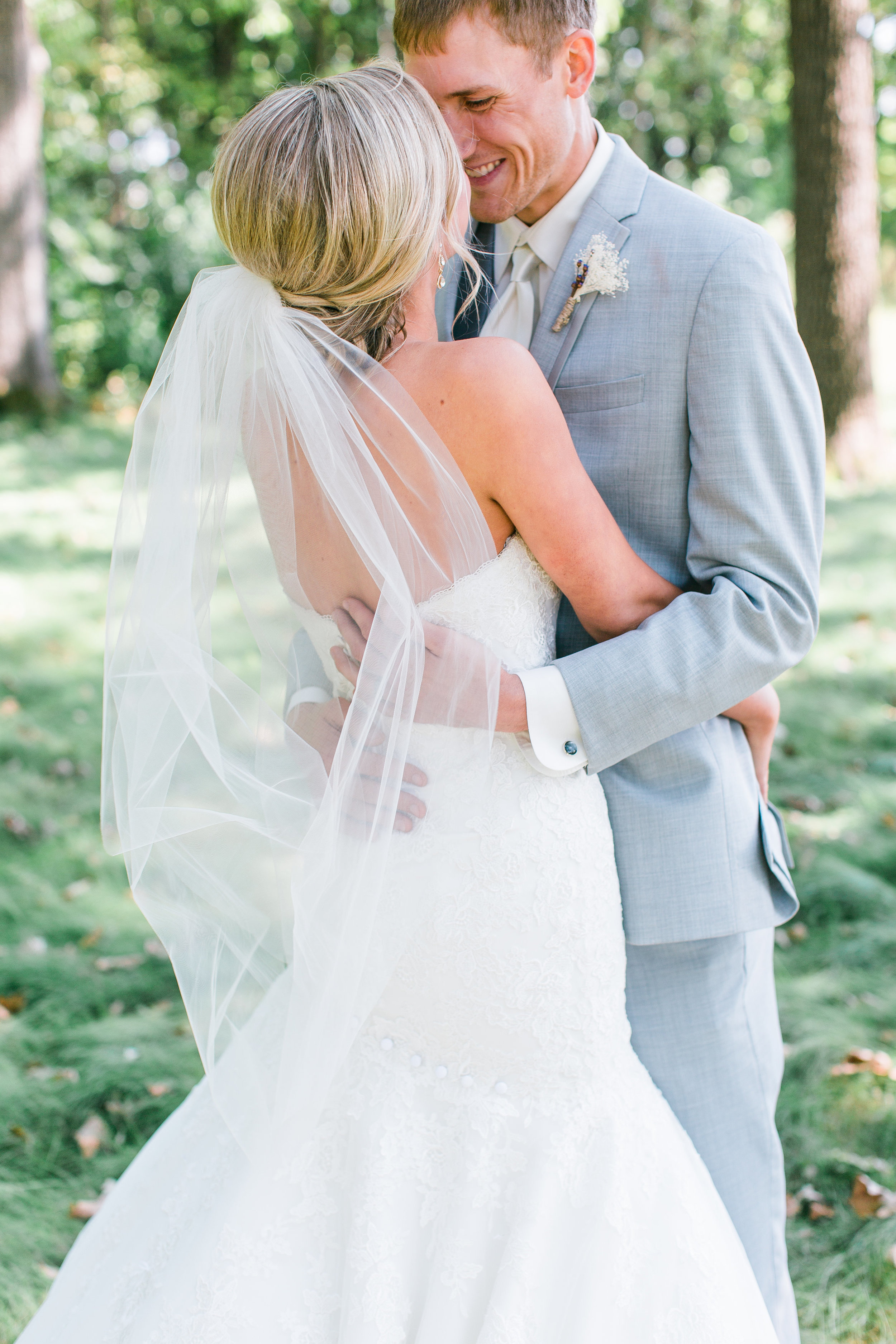 Minnesota bride and groom embracing on wedding day grey suit with veil Buffalo wedding Minnesota wedding photography Mallory Kiesow Photography 