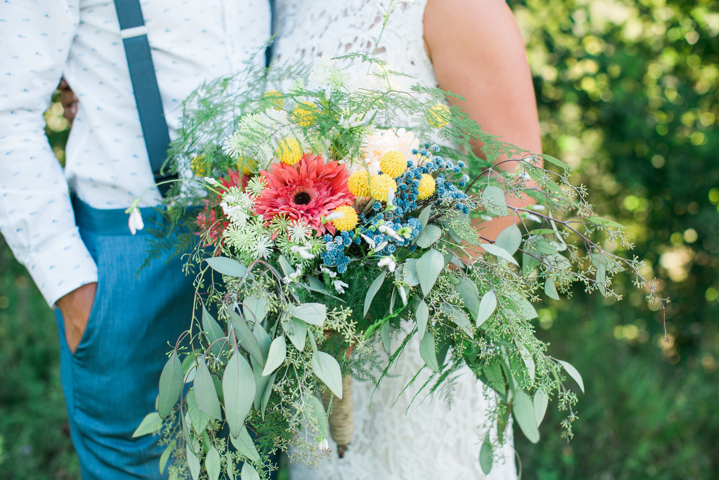 Rustic Minnesota wedding bride's bouquet and groom in suspenders and fish shirt Outpost Center wedding Minnesota wedding photography Mallory Kiesow Photography